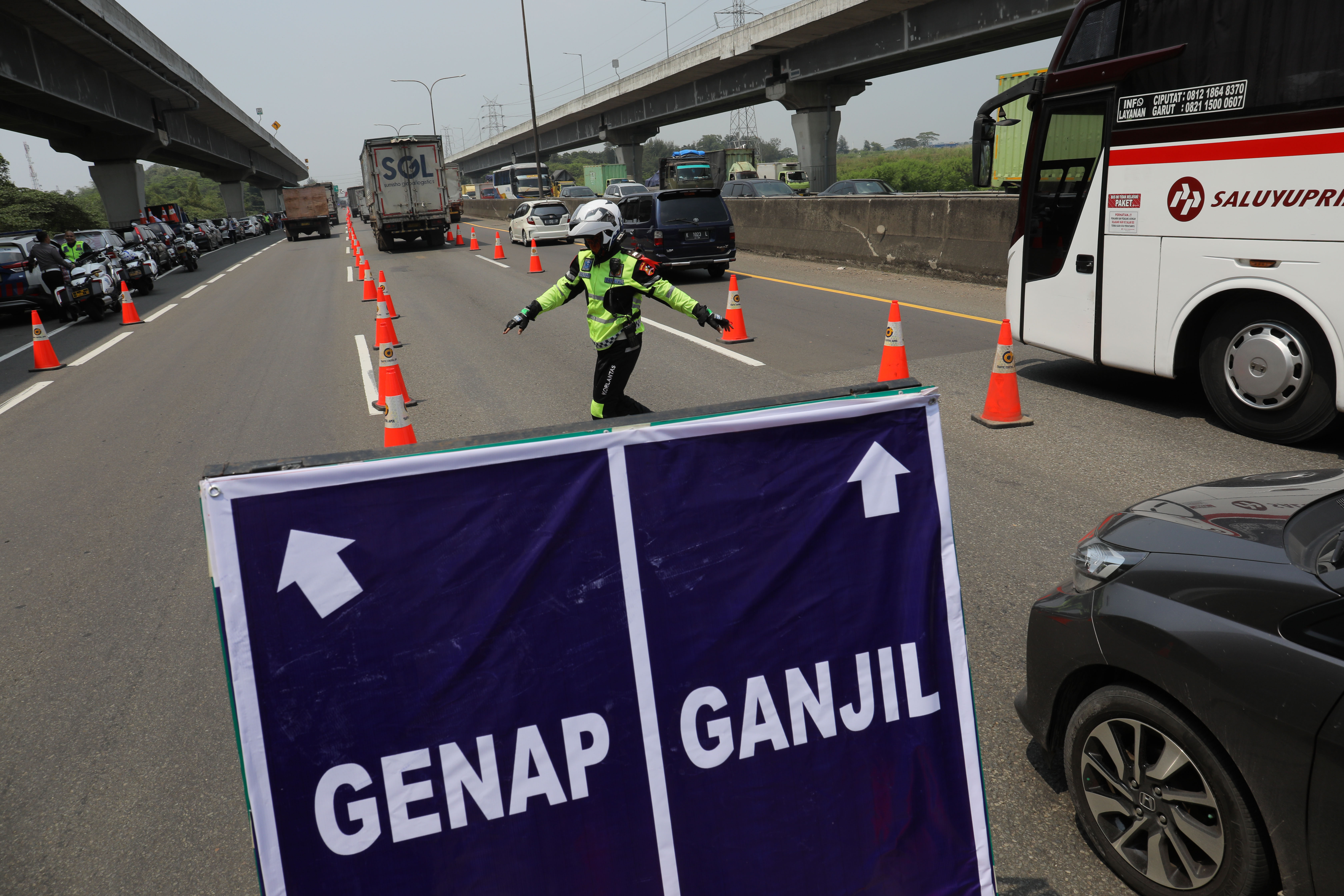Petugas mengatur lalu lintas di uji coba kebijakan ganjil genap di Tol Cikampek, Jawa Barat.