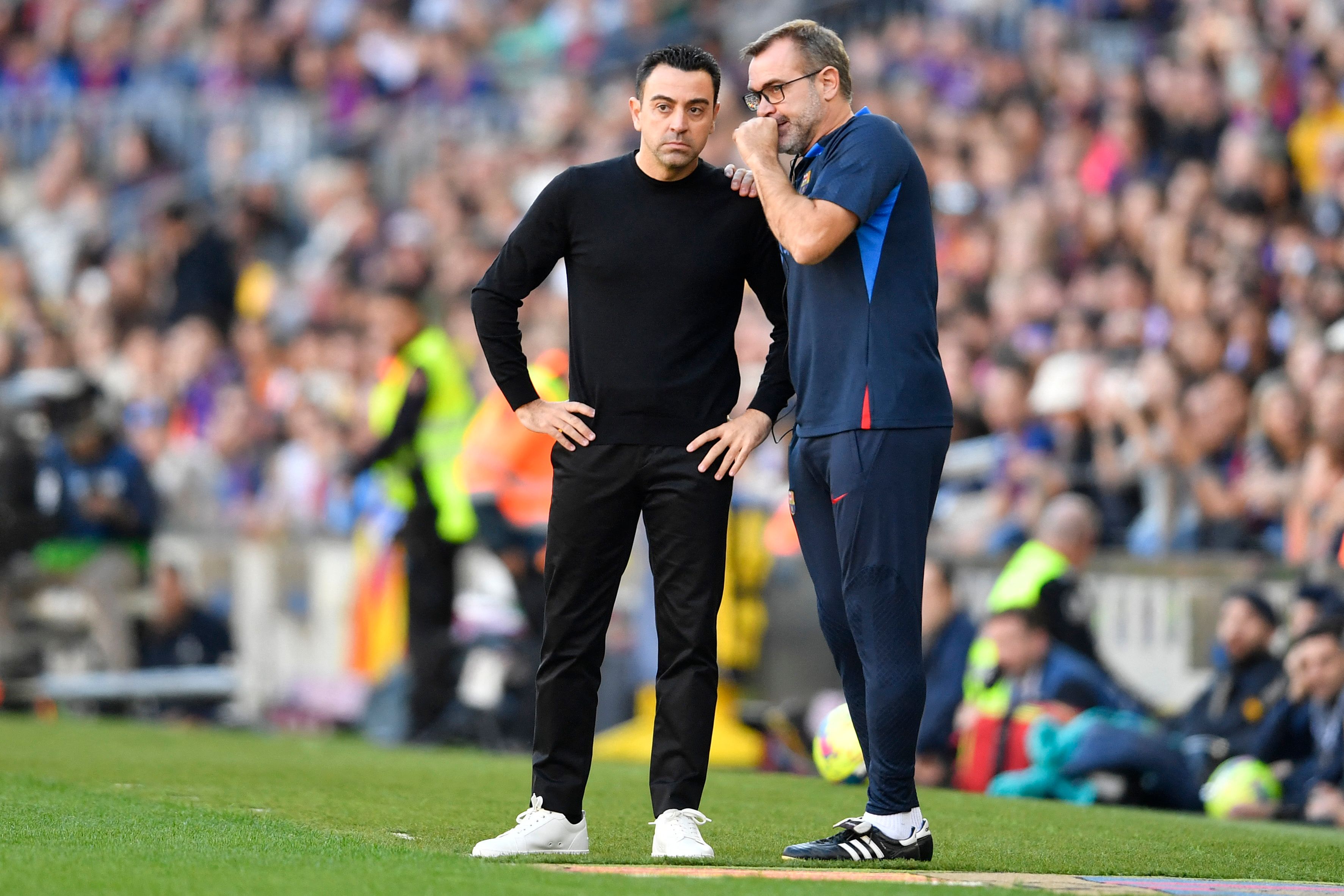 Pelatih Barcelona Xavi Hernandez (kiri) mendengarkan bisikan asisten pelatih Oscar Hernandez saat laga La Liga.