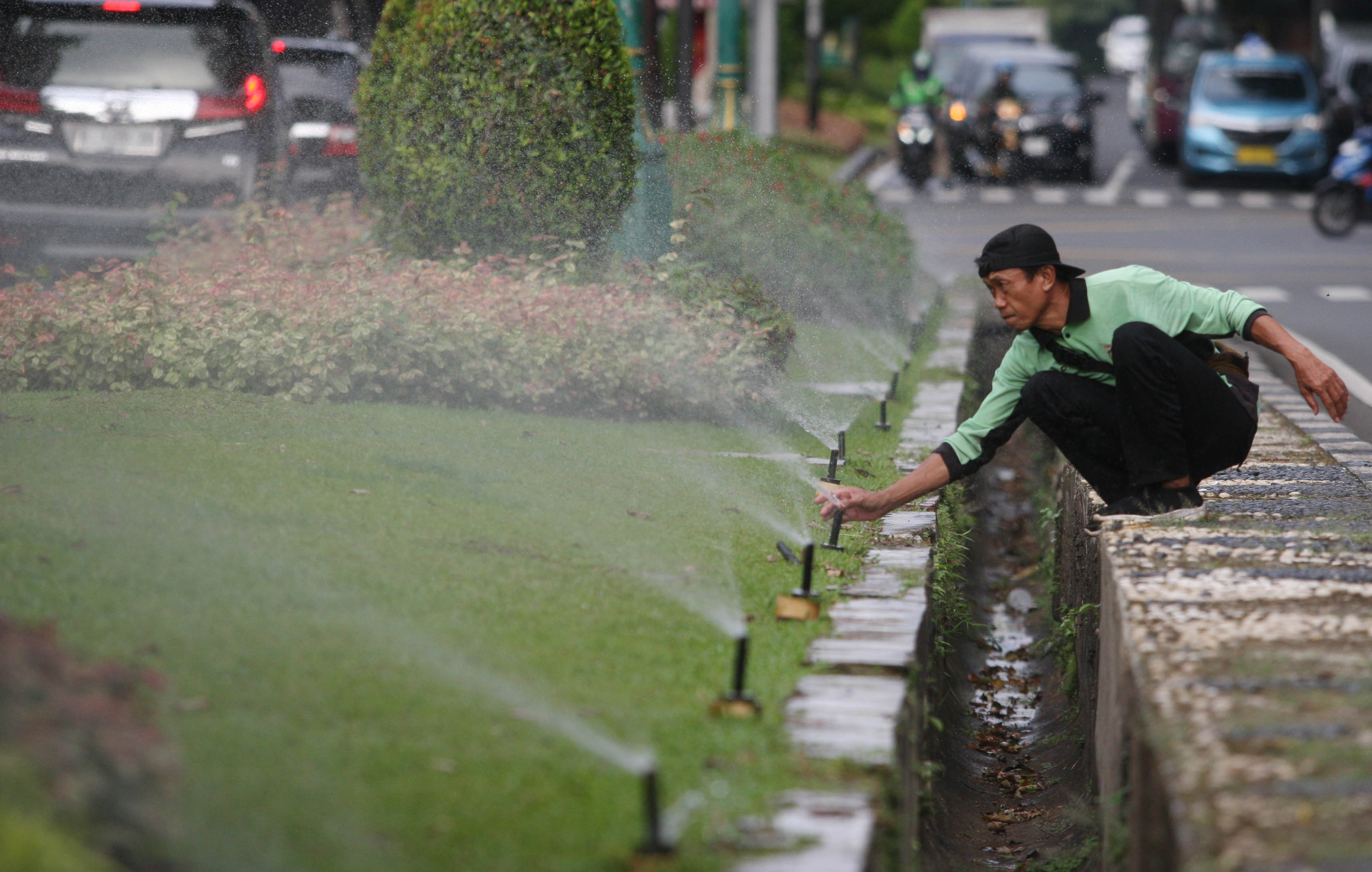 Ilustrasi: petugas Dinas Pertamanan dan Hutan Kota DKI Jakarta melakukan perawatan rumput dan taman kota menggunakan pompa mancur otomatis
