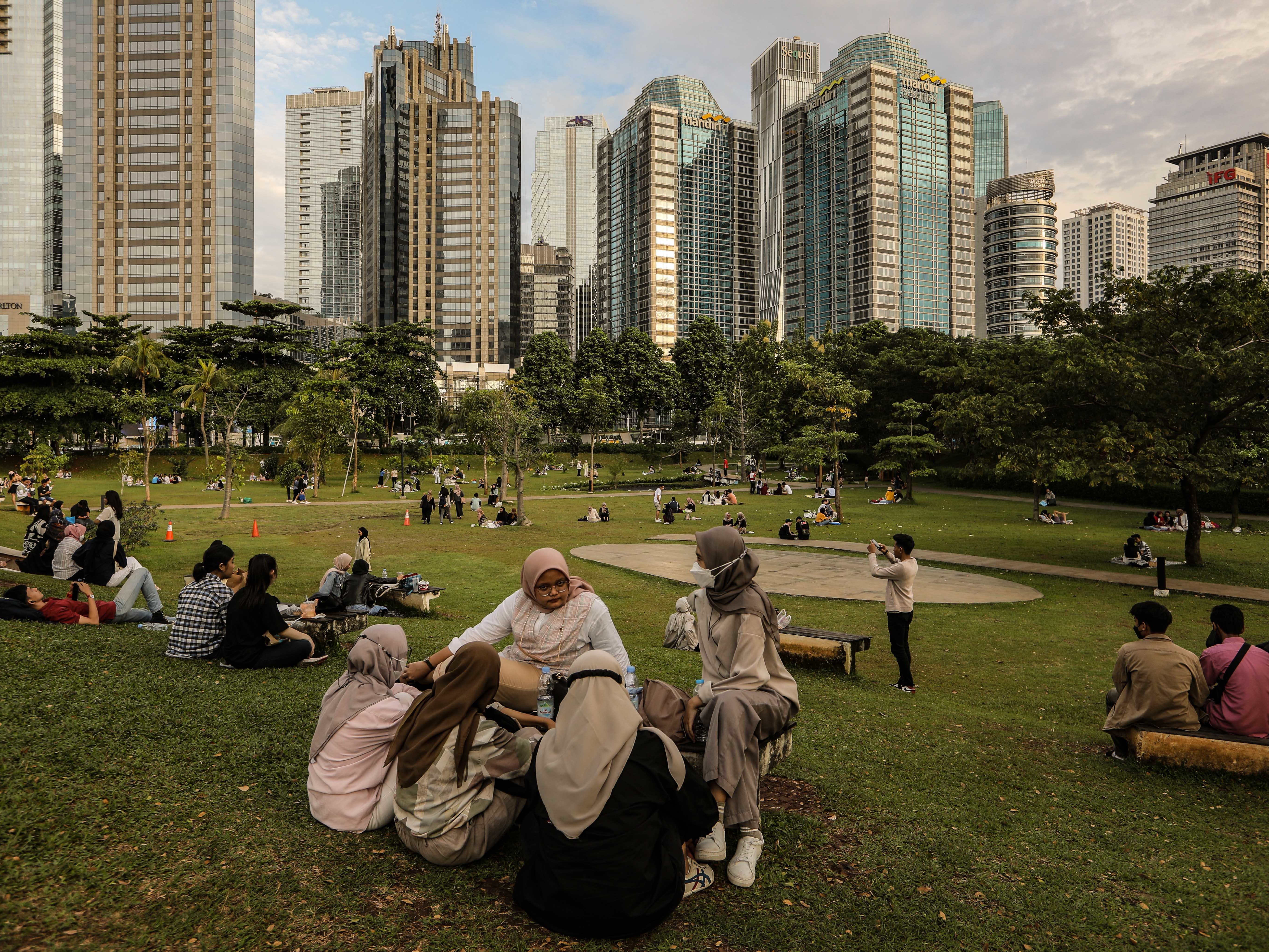 Warga mendatangi taman kota untuk menikmati sore dengan pemandangan gedung bertingkat Kota Jakarta di Hutan Kota, Jakarta.