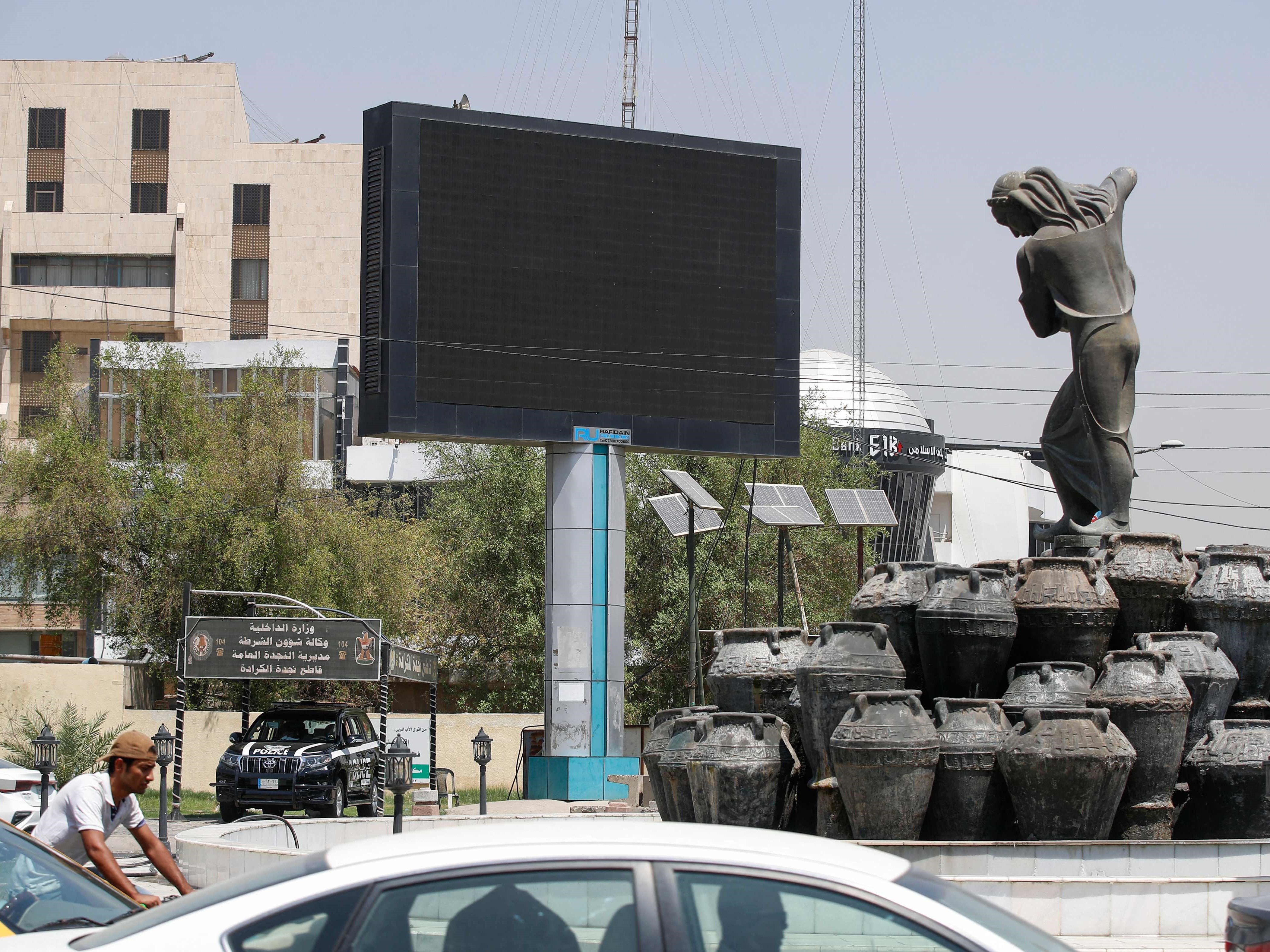 Kendaraan melewati layar iklan tertutup di alun-alun Kahramana di Baghdad pada 20 Agustus 2023.
