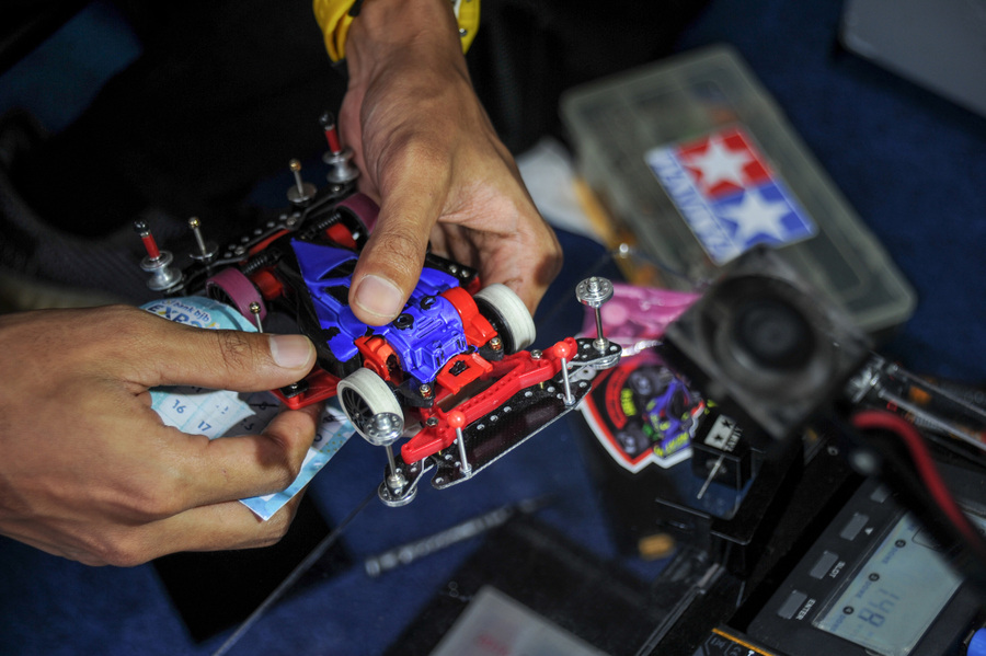 Seseorang tengah merakit mobil tamiya.