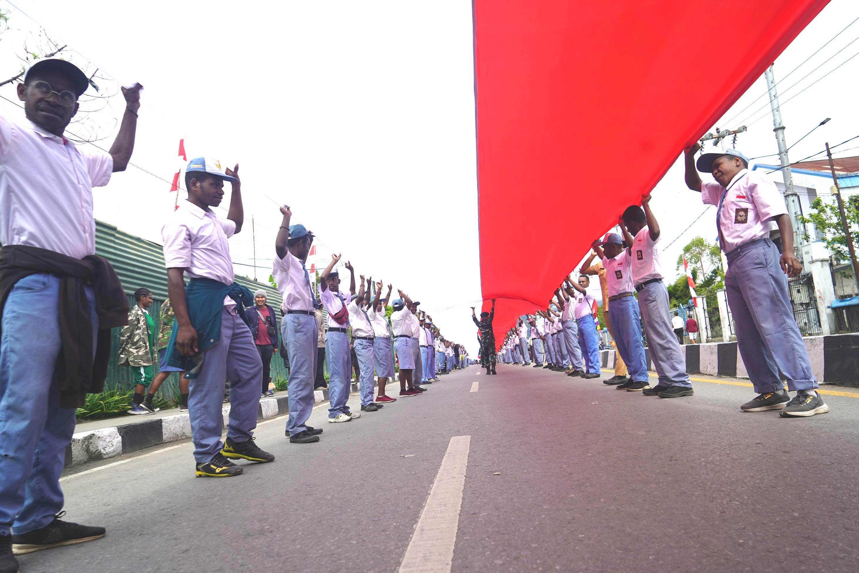 Ratusan siswa dan masyarakat membentangkan bendera Merah Putih sepanjang 2023 meter di Jln Yos Sudarso, Wamena, Papua Pegunungan.