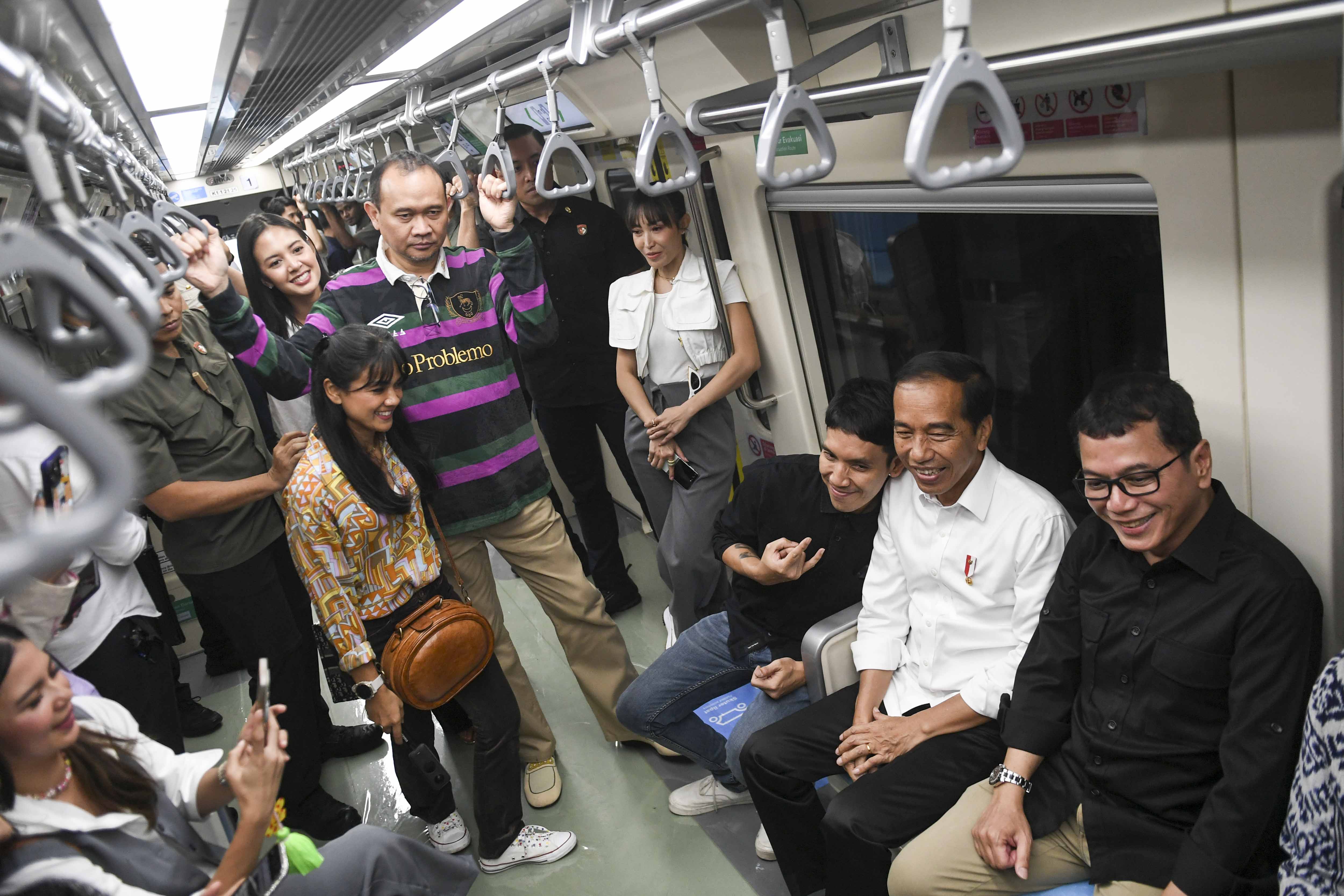 Presiden Joko Widodo (kedua kanan) berbincang dengan para artis saat menaiki LRT Jabodebek.