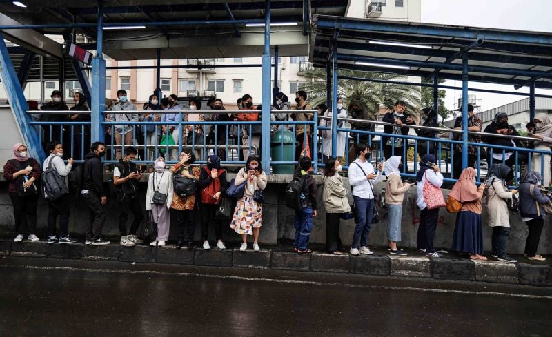 Para calon penumpang mengantre di halte untuk menaiki TransJakarta