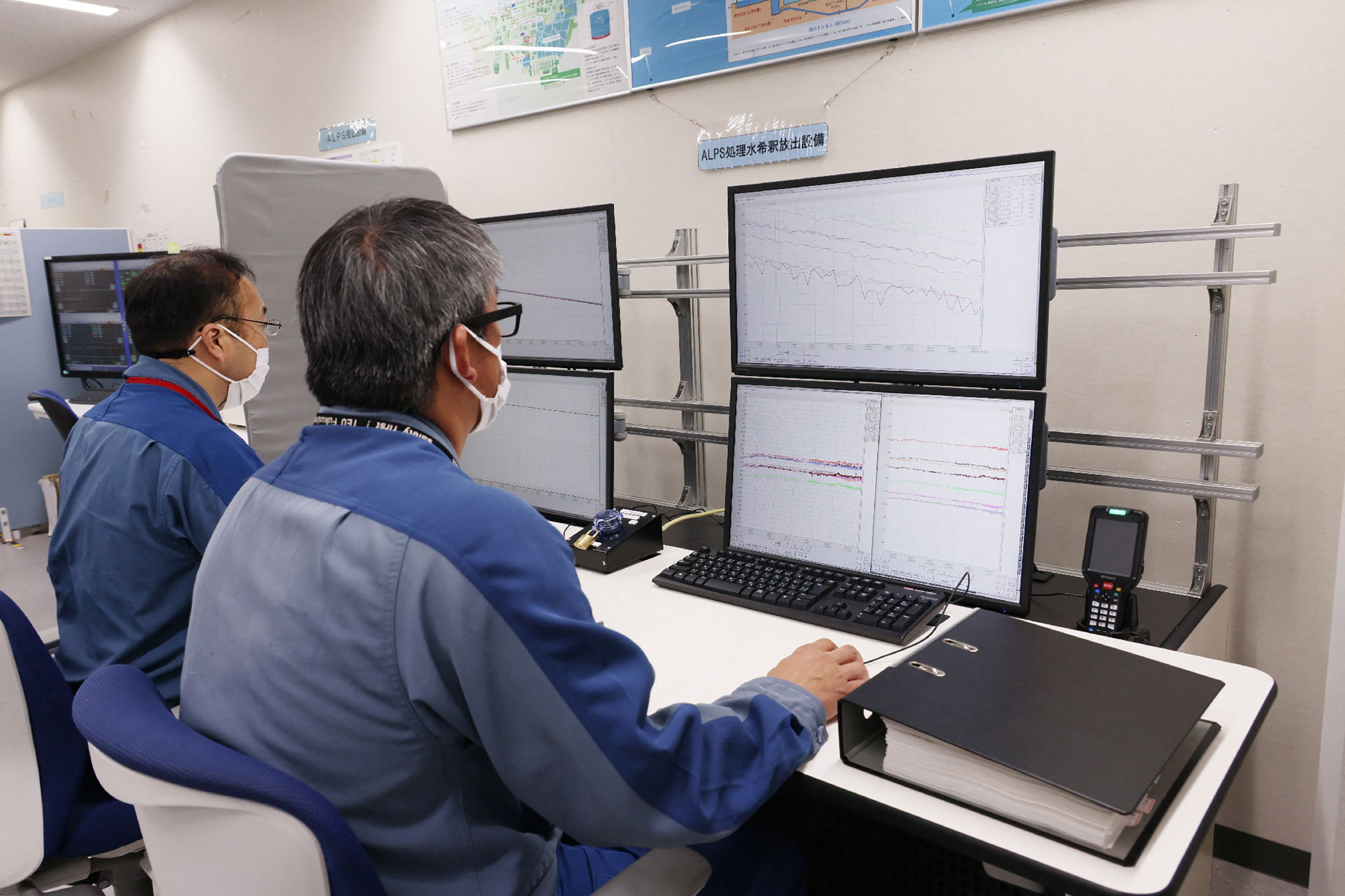 Para pekerja berada di ruang kendali mengawasi pelepasan air limbah dari PLTN Fukushima.