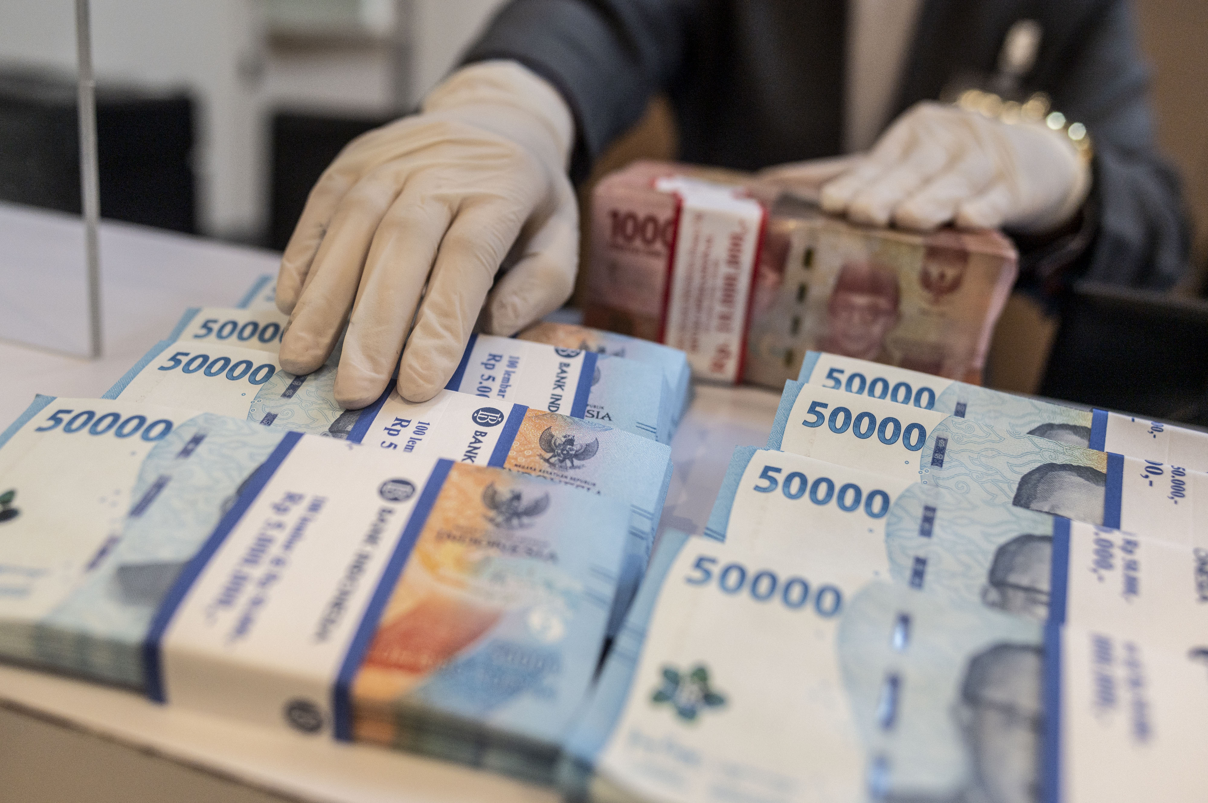  Karyawan meletakkan uang pecahan Rp50.000 di BNI KC Mega Kuningan, Jakarta.