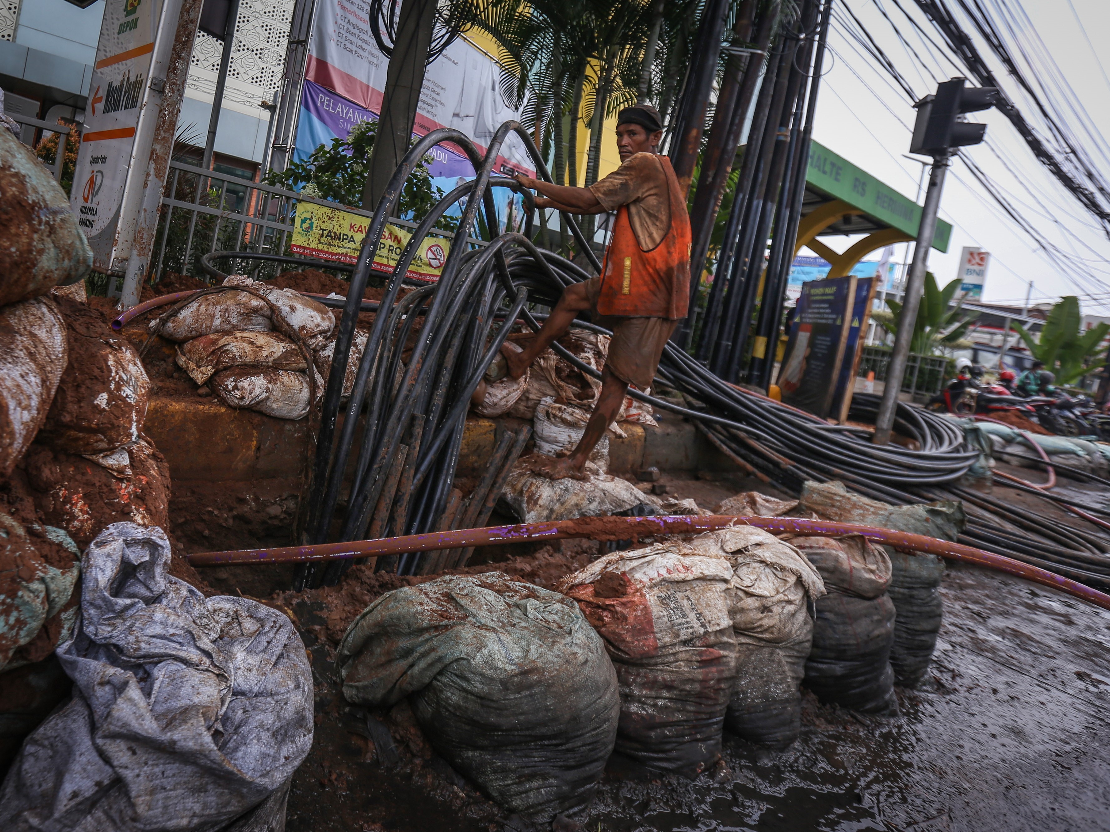 Pekerja menyelesaikan instalasi kabel bawah tanah di Jalan Siliwangi, Depok, Jawa Barat.