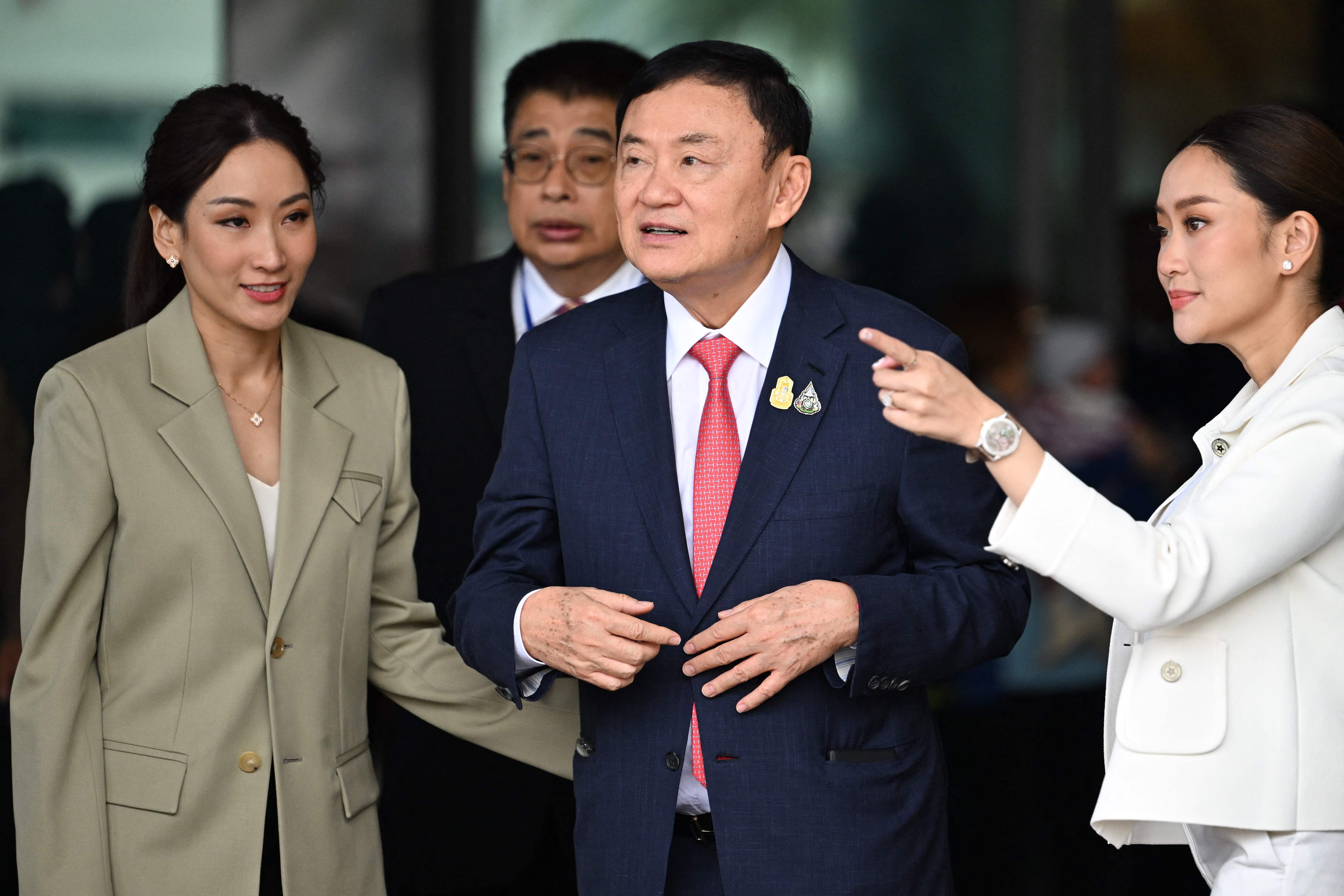 Mantan Perdana Menteri Thailand Thaksin Shinawatra (tengah) saat kembali ke negaranya diapit kedua putrinya.
