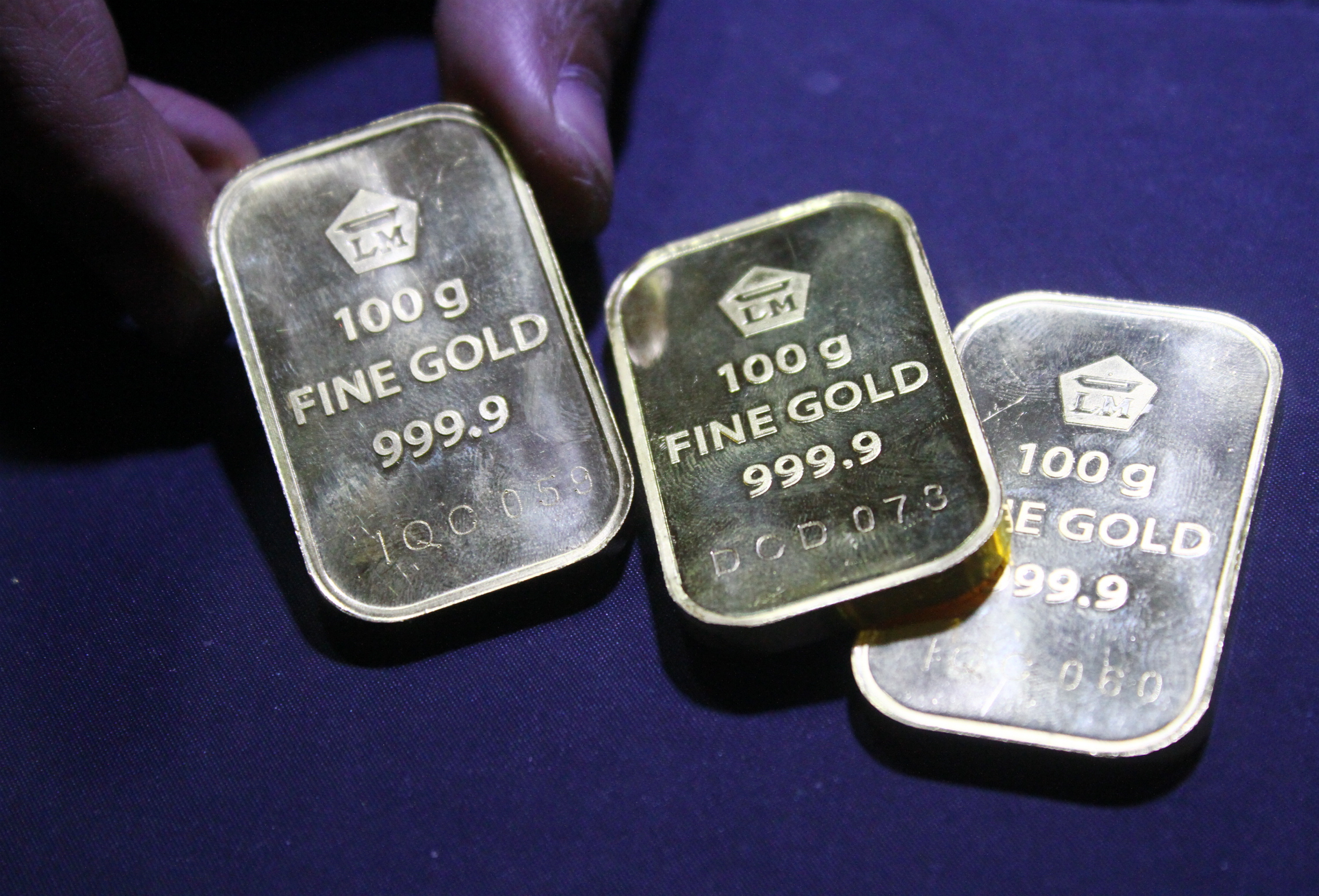 Petugas memperlihatkan emas batangan 100 gram di sebuah gerai toko emas di Malang, Jawa Timur, Selasa (24/11).