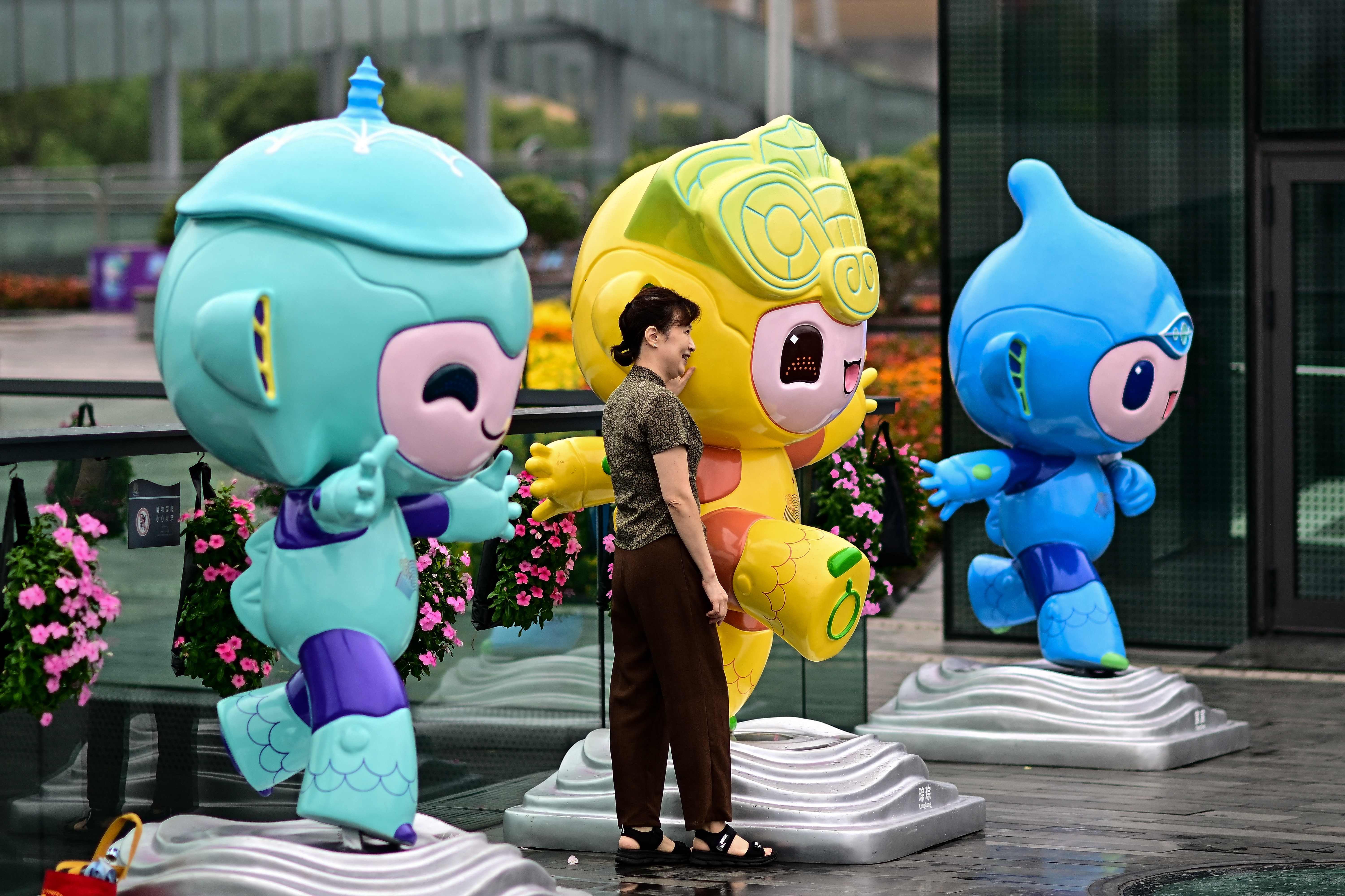 Seorang wanita berpose untuk foto bersama maskot Asian Games 2022 (Kiri-Kanan) Chenchen, Congcong, dan Lianlian