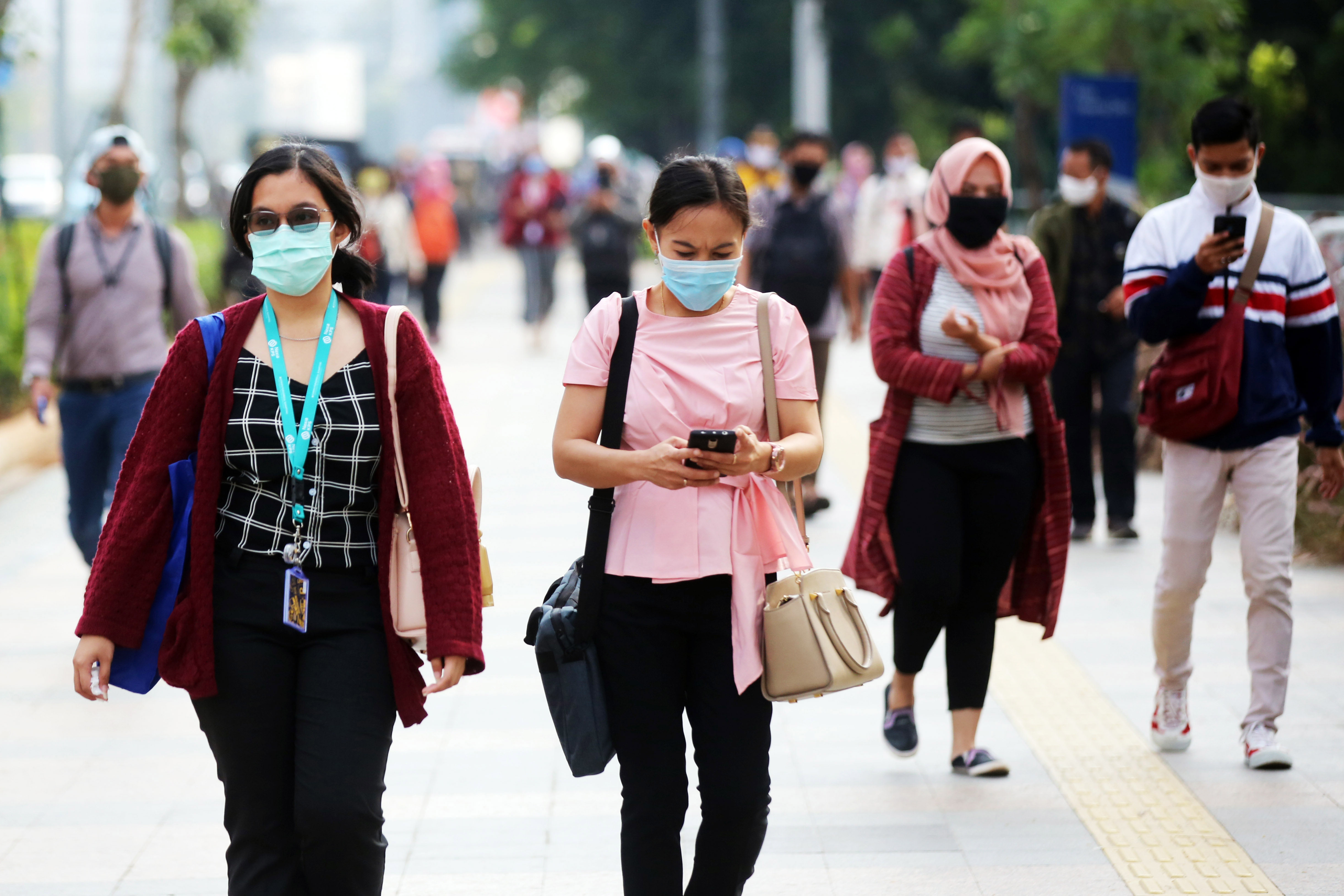 Pekerja menggunakan masker menuju kantornya melewati trotoar di kawasan Sudirman, Jakarta, Senin (8/6/2020).
