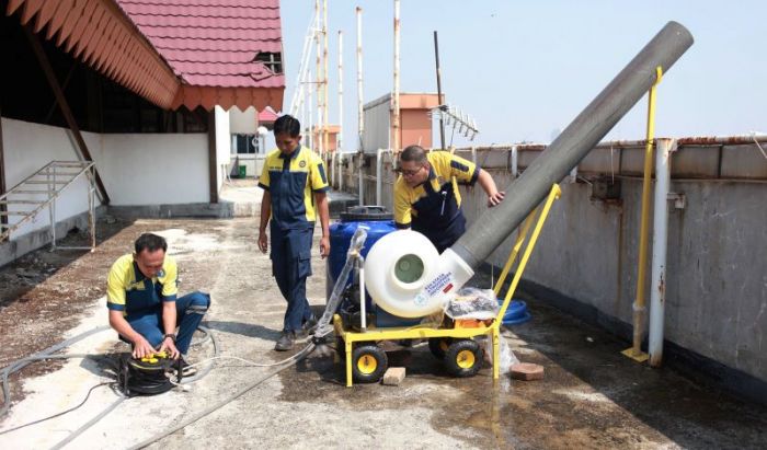 Pekerja memasang water mist generator di atap gedung.