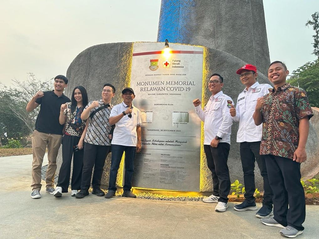 Tim dosen dan mahasiswa UPH serta tim PMI berfoto di depan Monumen Memorial Relawan Covid-19 PMI di Solear, Tangerang.