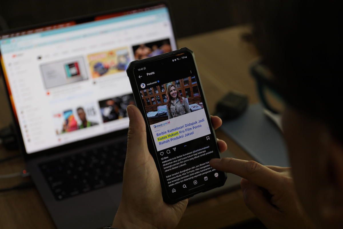 Warga melihat berita online terkait perkembangan kasus rumah produksi film porno di Jakarta Selatan.
