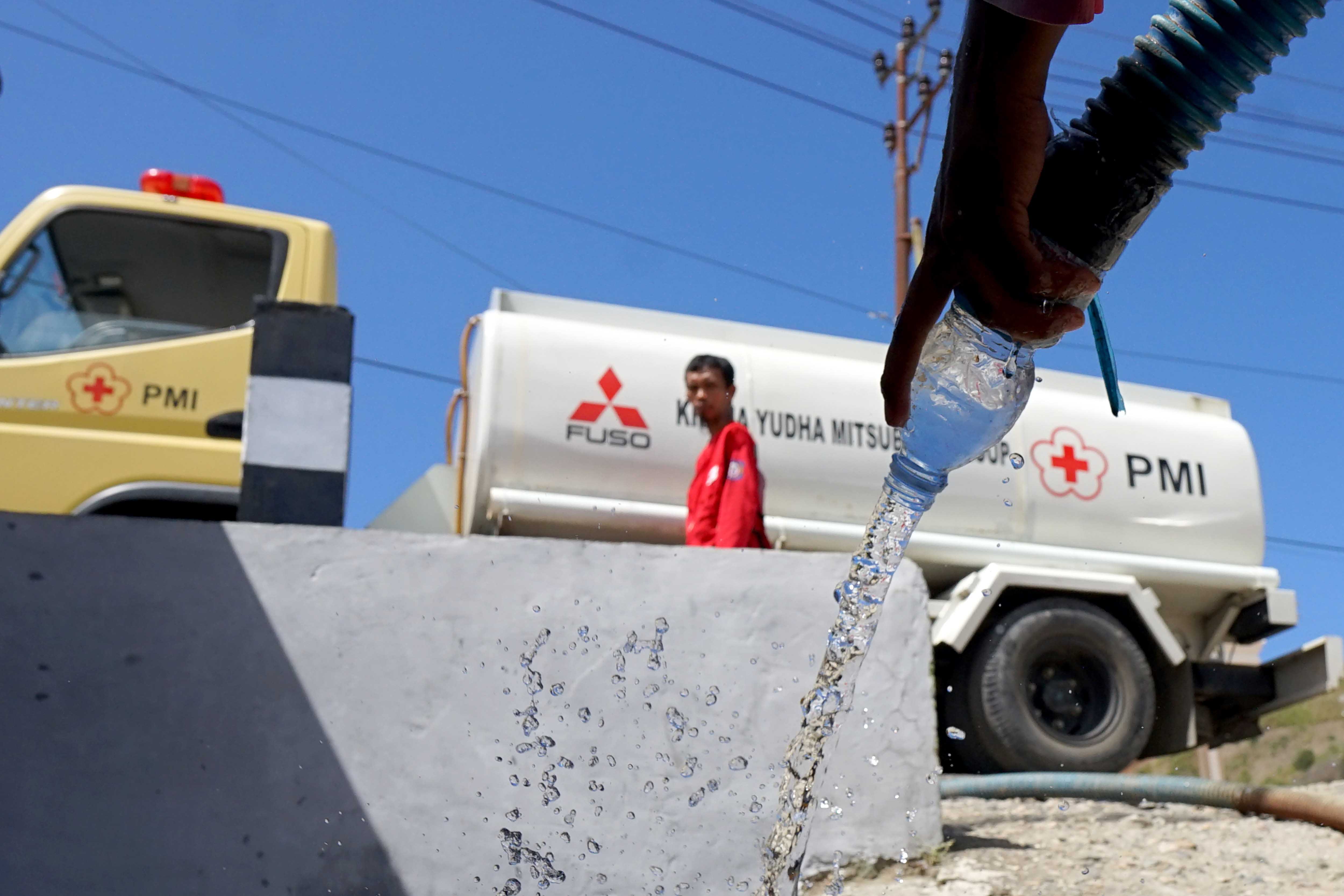 Ilustrasi.  Petugas PMI mengisi air ke dalam ember dan galon air milik warga di Desa Buata, Kabupaten Bone Bolango.