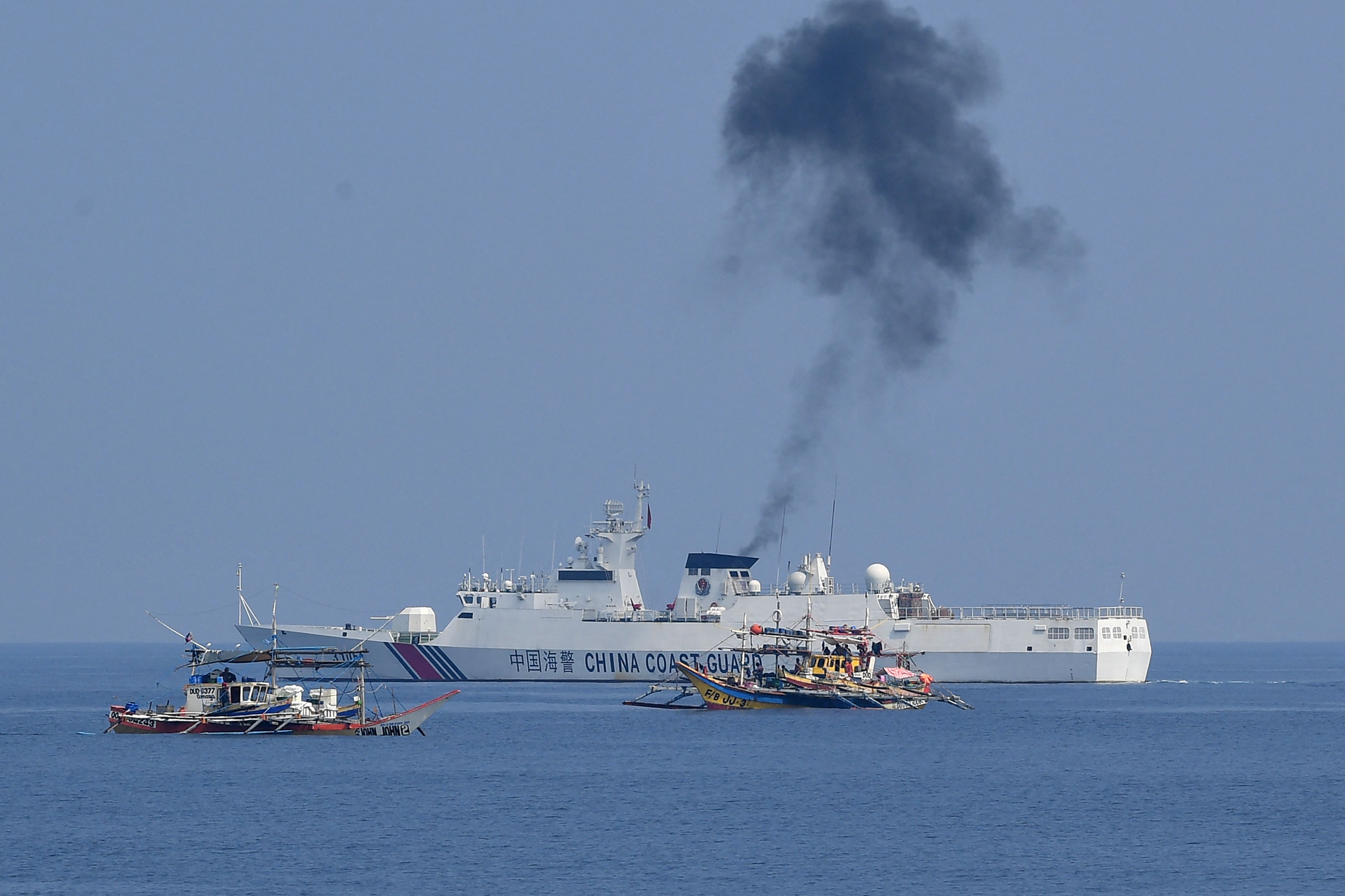 Kapal penjaga pantai Tiongkok (belakang) membayangi kapal nelayan Filipina yang berlabuh di dekat Scarborough Shoal yang disengketakan.