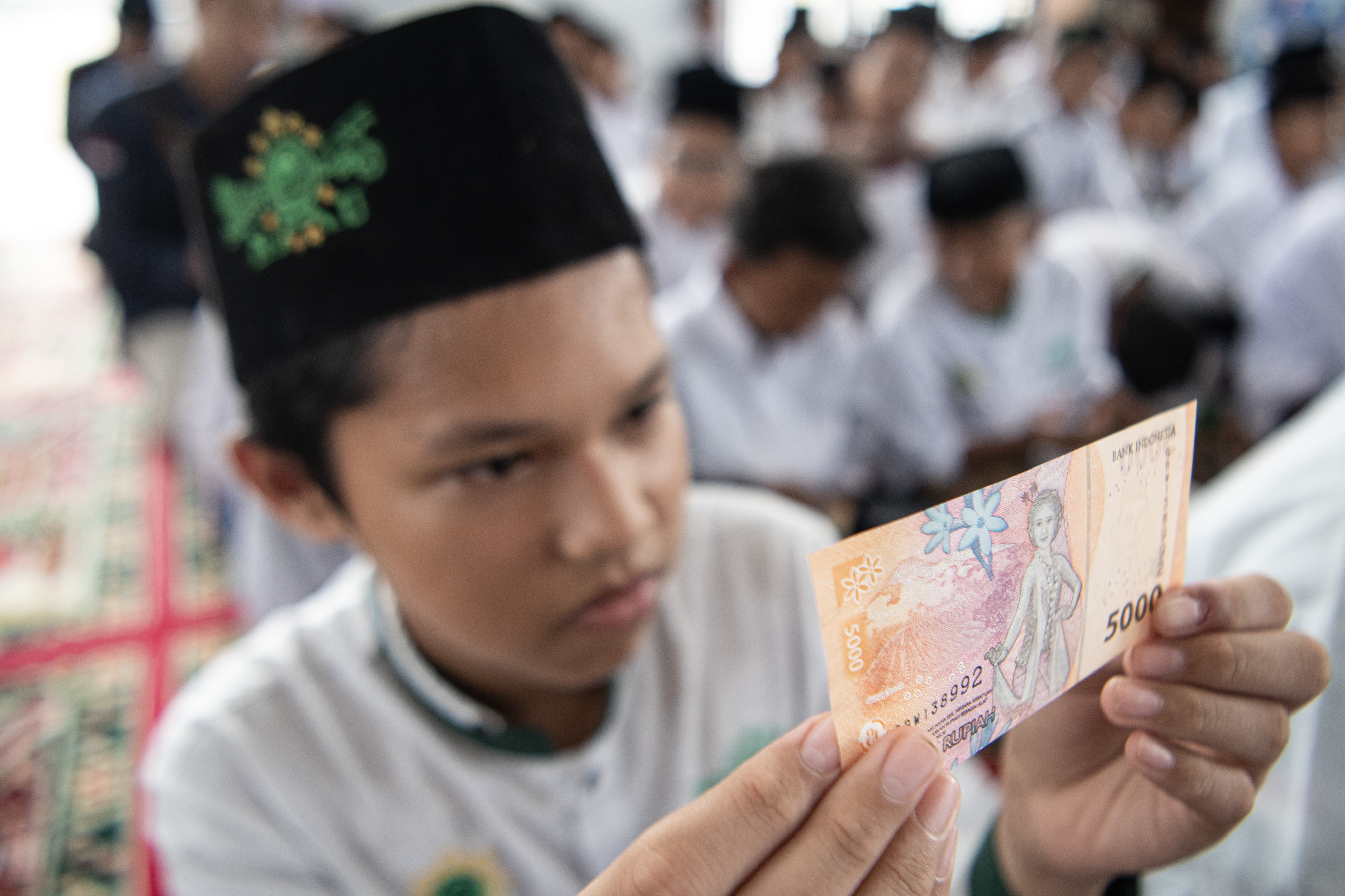 Santri mengamati uang pecahan Rp5 ribu saat peluncuran Program Gerakan Santri Cinta Rupiah Se-Sumatera Selatan.