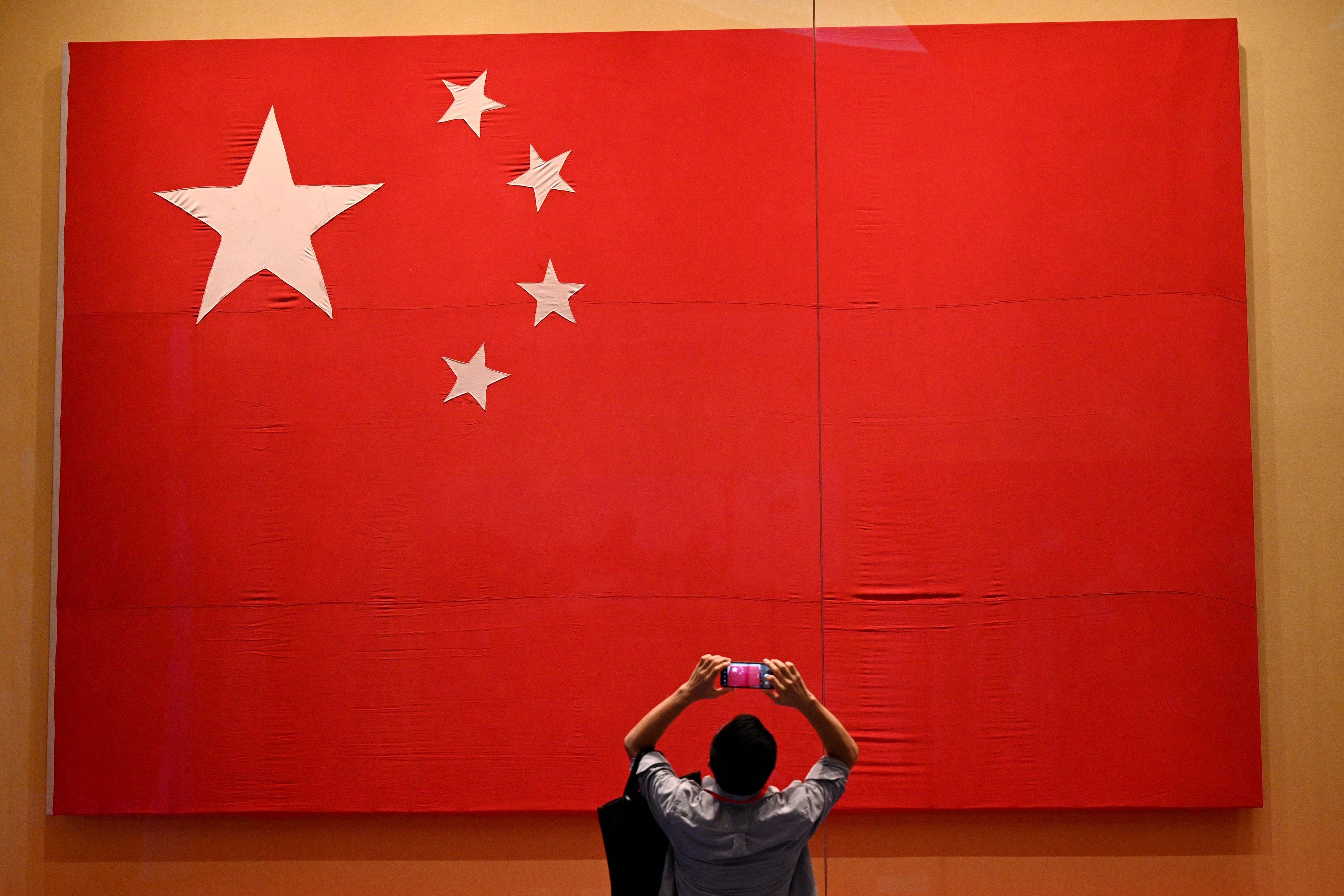 Seorang jurnalis memotret bendera Tiongkok di Museum Partai Komunis Tiongkok di Beijing, Jumat (25/6/2021).