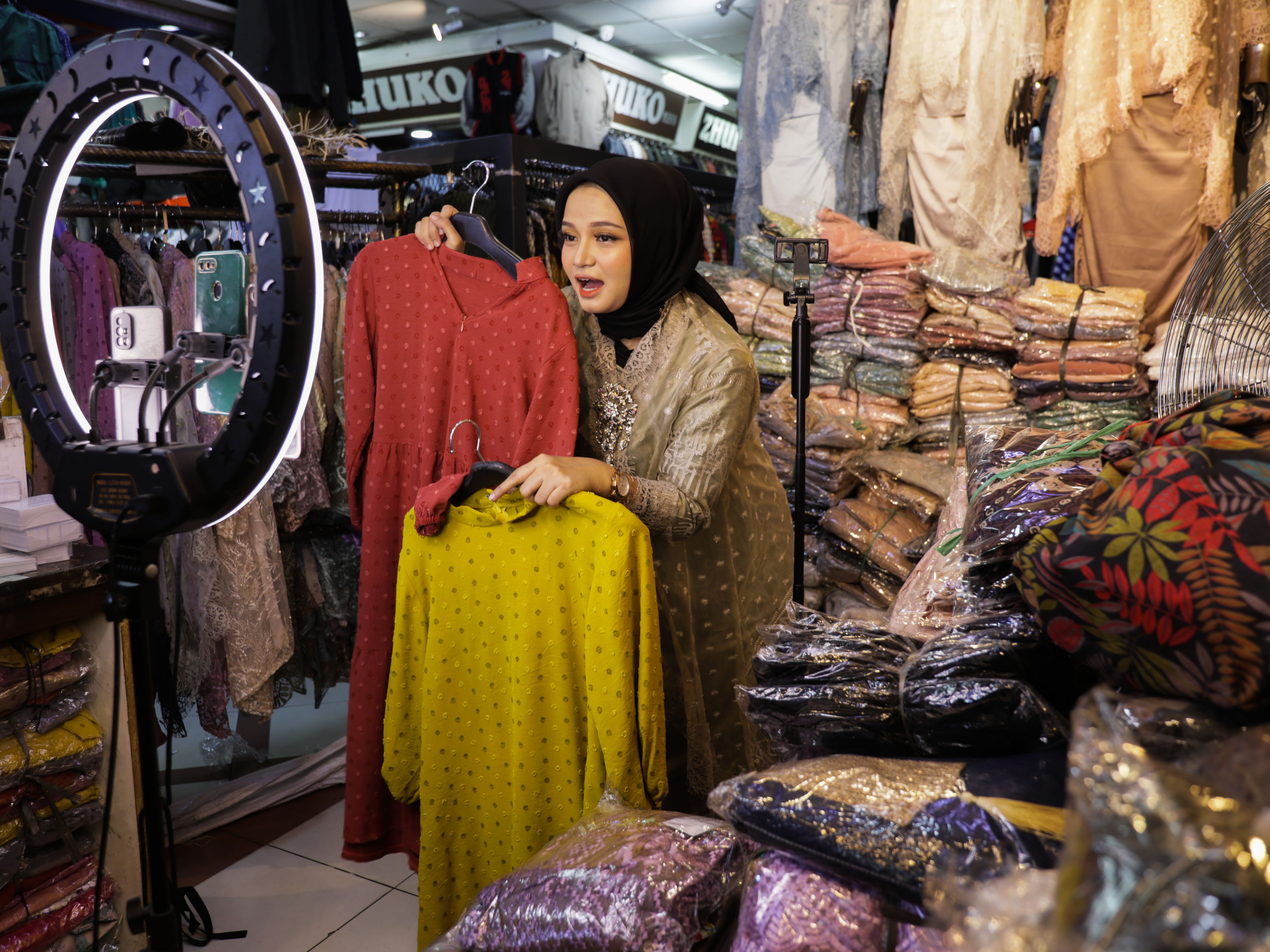 Ucy menawarkan pakaian muslim wanita melalui siaran streaming di Pasar Tanah Abang Blok A, Jakarta.