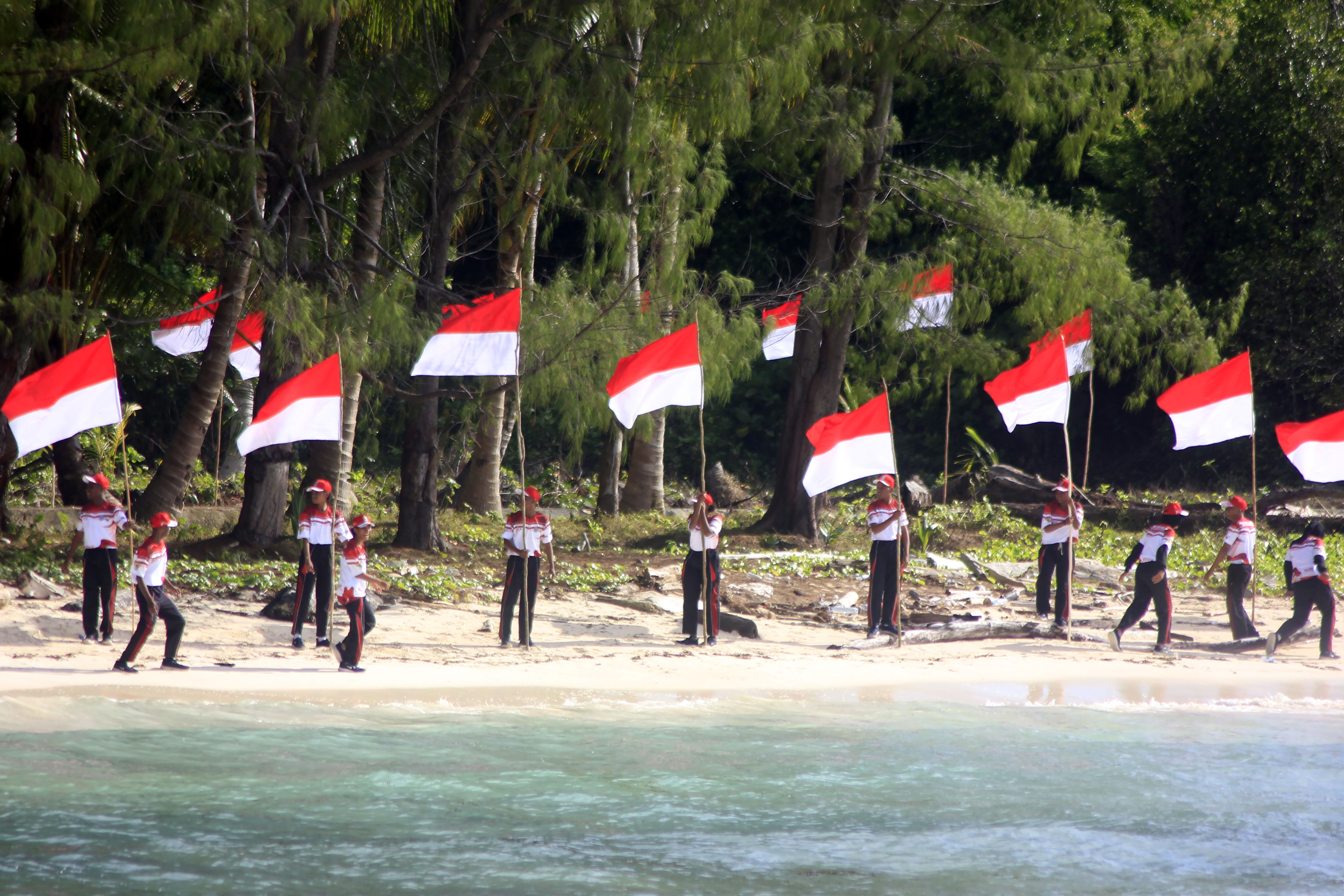 Pelajar memasang bendera Merah Putih di pulau terluar Pantai Kepulauan Fani Kabupaten Raja Ampat, Papua Barat Daya, Senin (21/8).