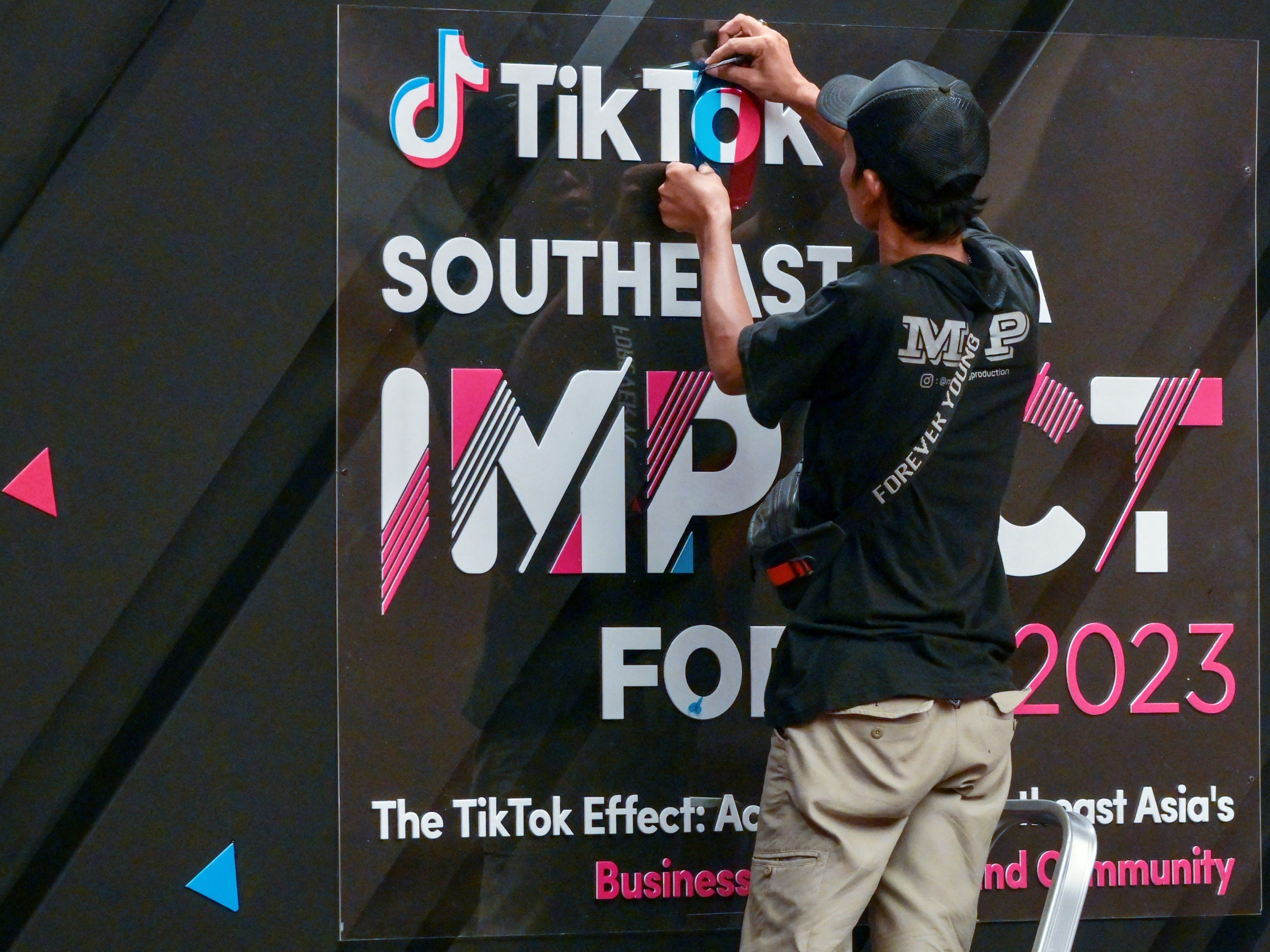 Seorang pekerja menyelesaikan papan tanda di depan TikTok Southeast Asia Impact Forum 2023 di Jakarta pada 15 Juni 2023.