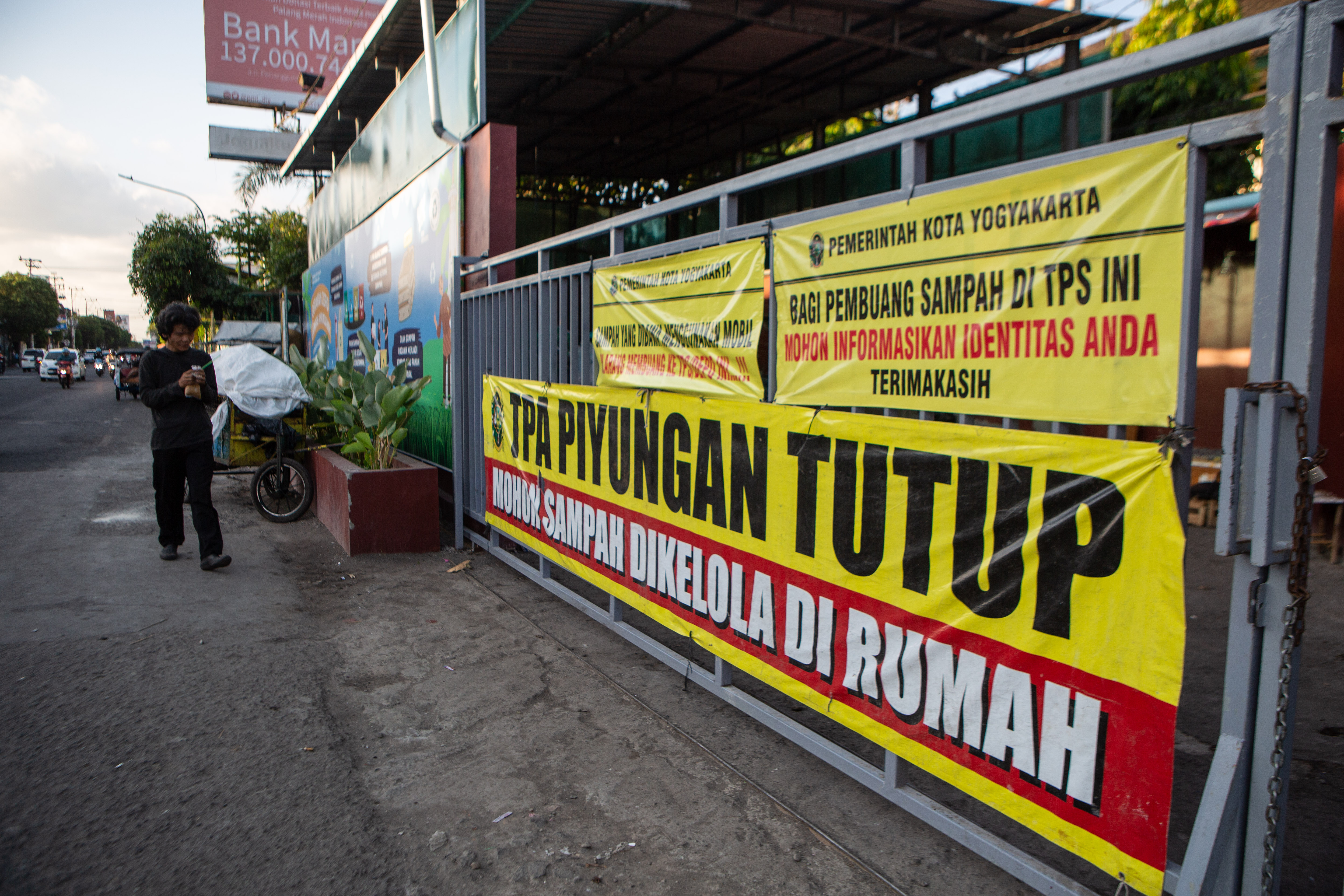 Warga melintas di dekat tempat pembuangan sampah sementara, imbas ditutupnya TPA Piyungan, pada Juli 2023.