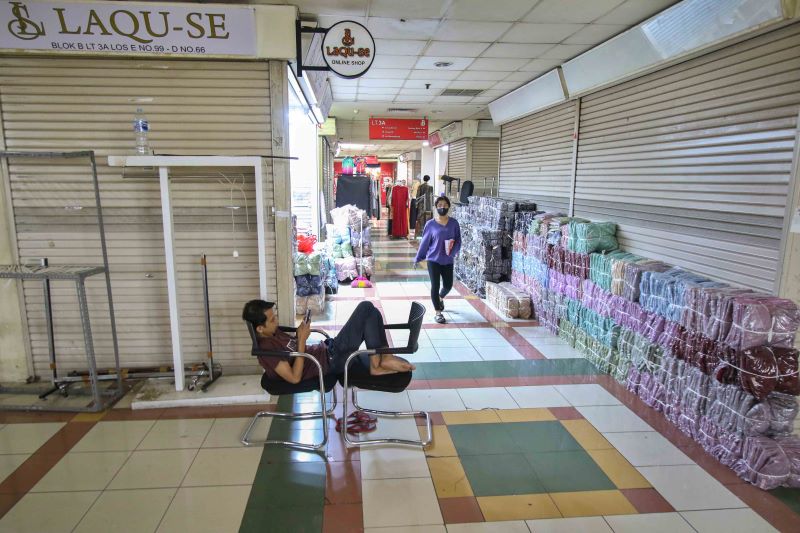 Pedagang menunggu konsumen di kiosnya di antara kios yang sebagian tutup di Blok B Pasar Tanah Abang, Jakarta Pusat.