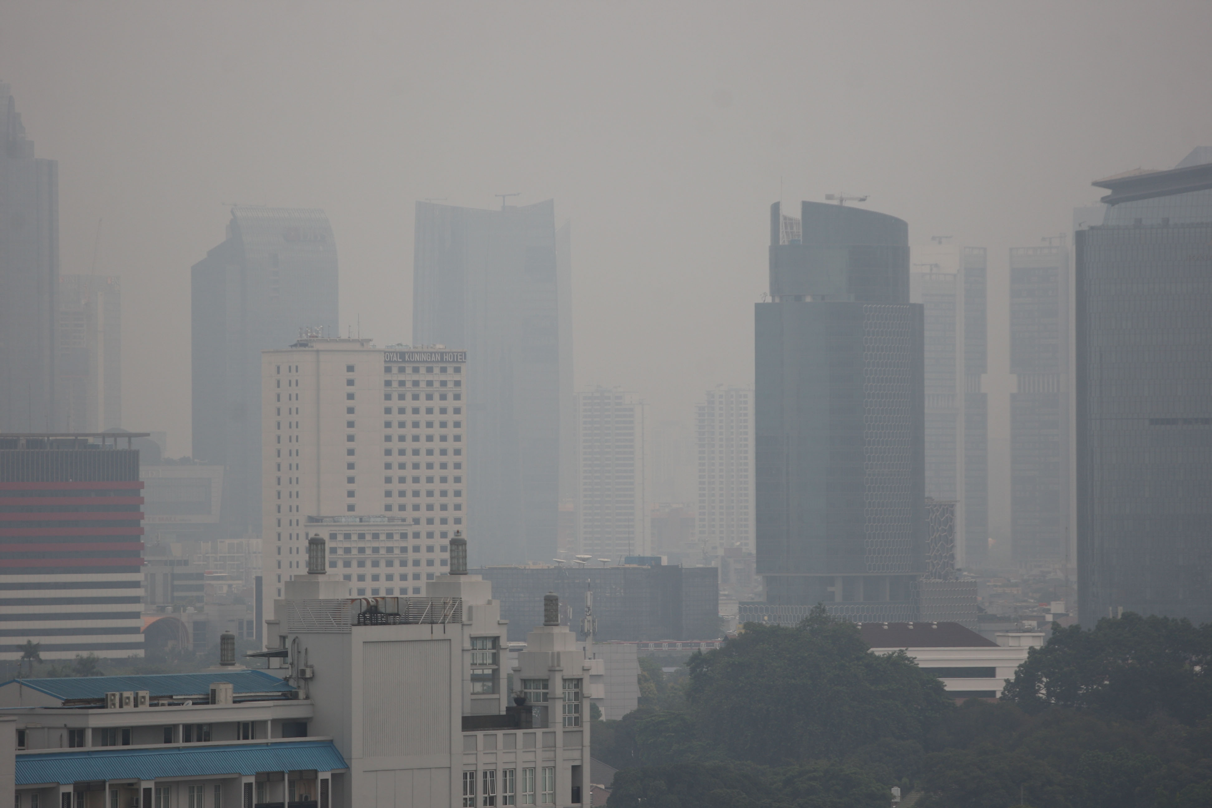 Lanskape gedung bertingkat yang diselimuti kabut polusi udara di Jakarta.
