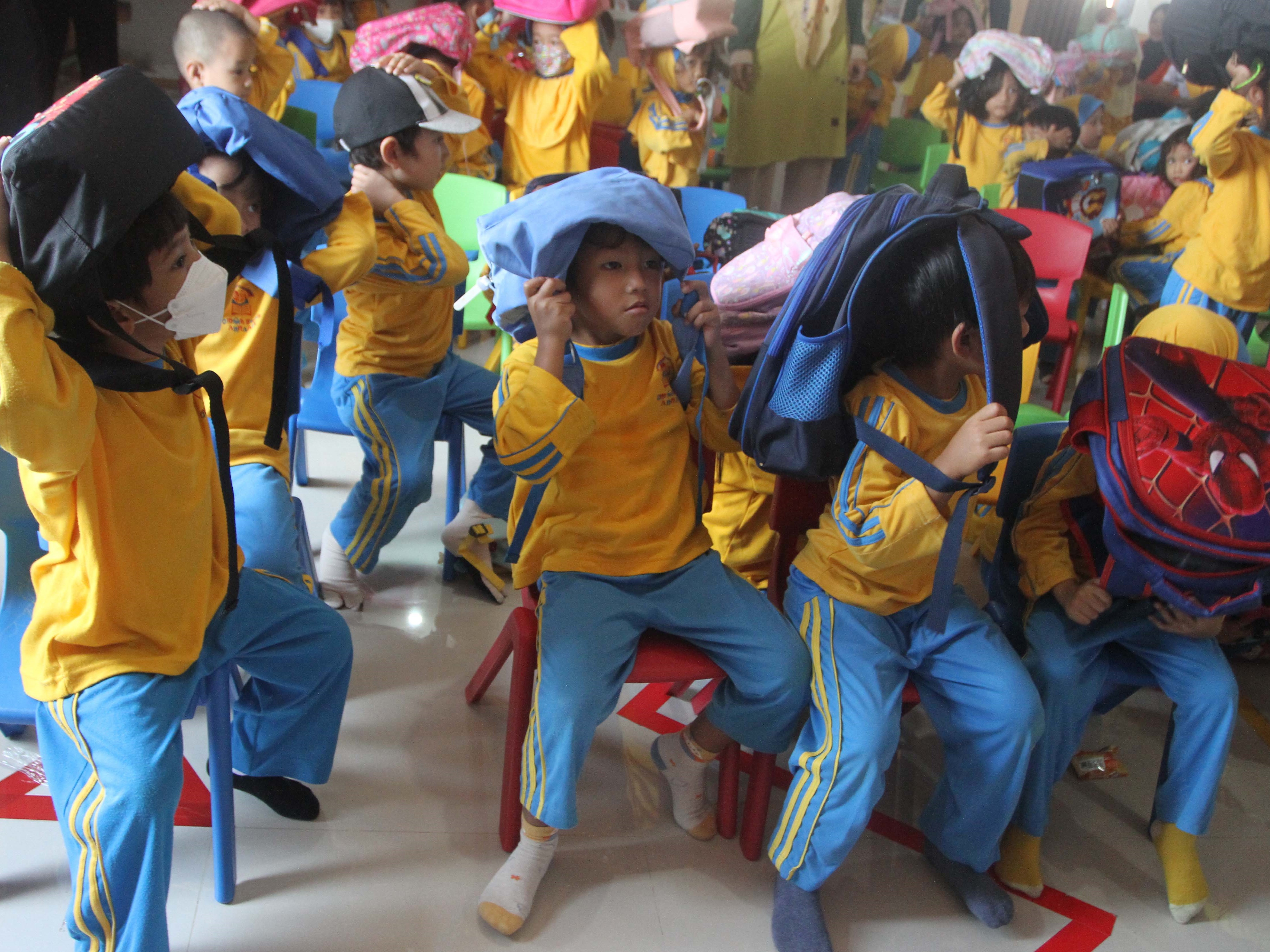 Sejumlah murid melindungi kepala dengan tas sekolah dalam simulasi kesiagaan bencana gempa bumi di PAUD Terpadu Omah Bocah Annaafi Malang.