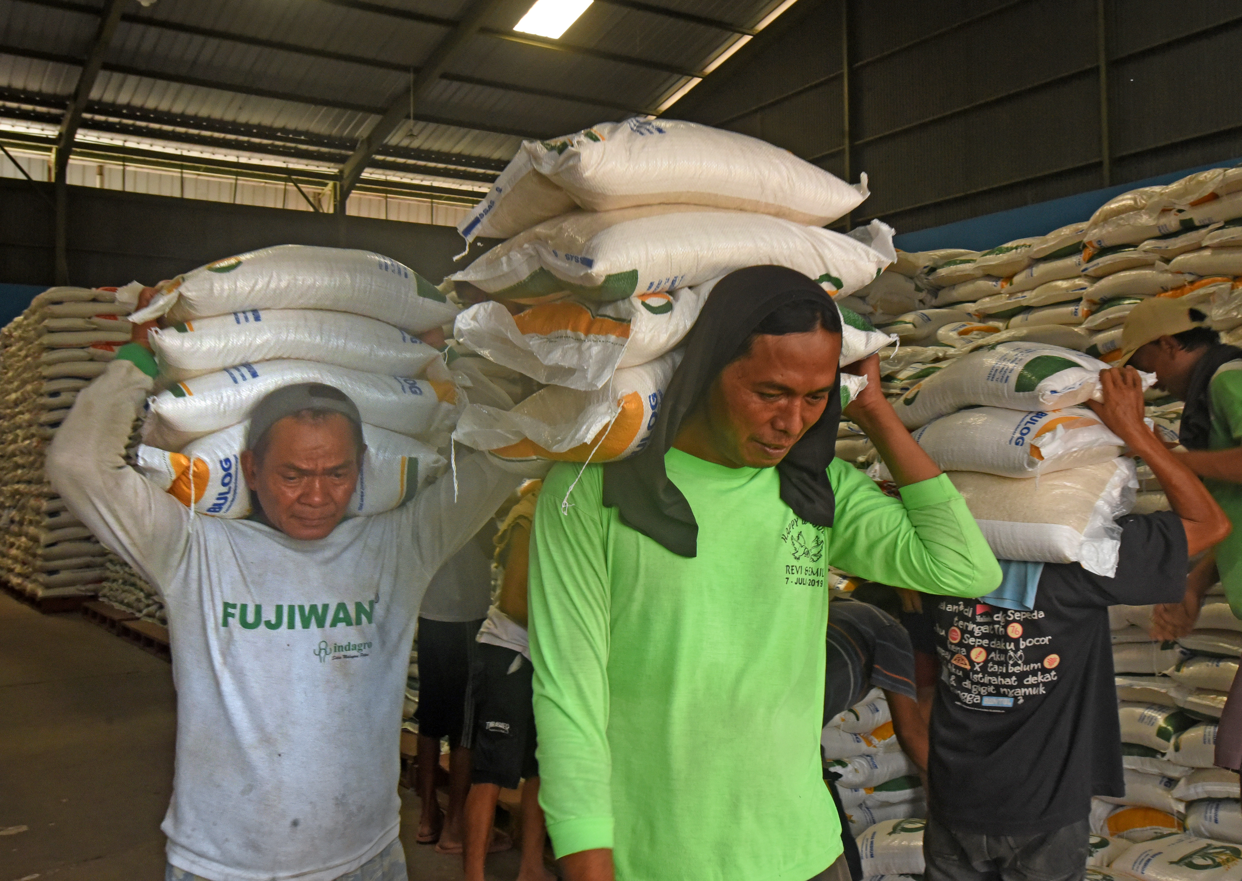 Sejumlah pekerja mengangkut beras bantuan pemerintah untuk didistribusikan ke keluarga penerima manfaat.