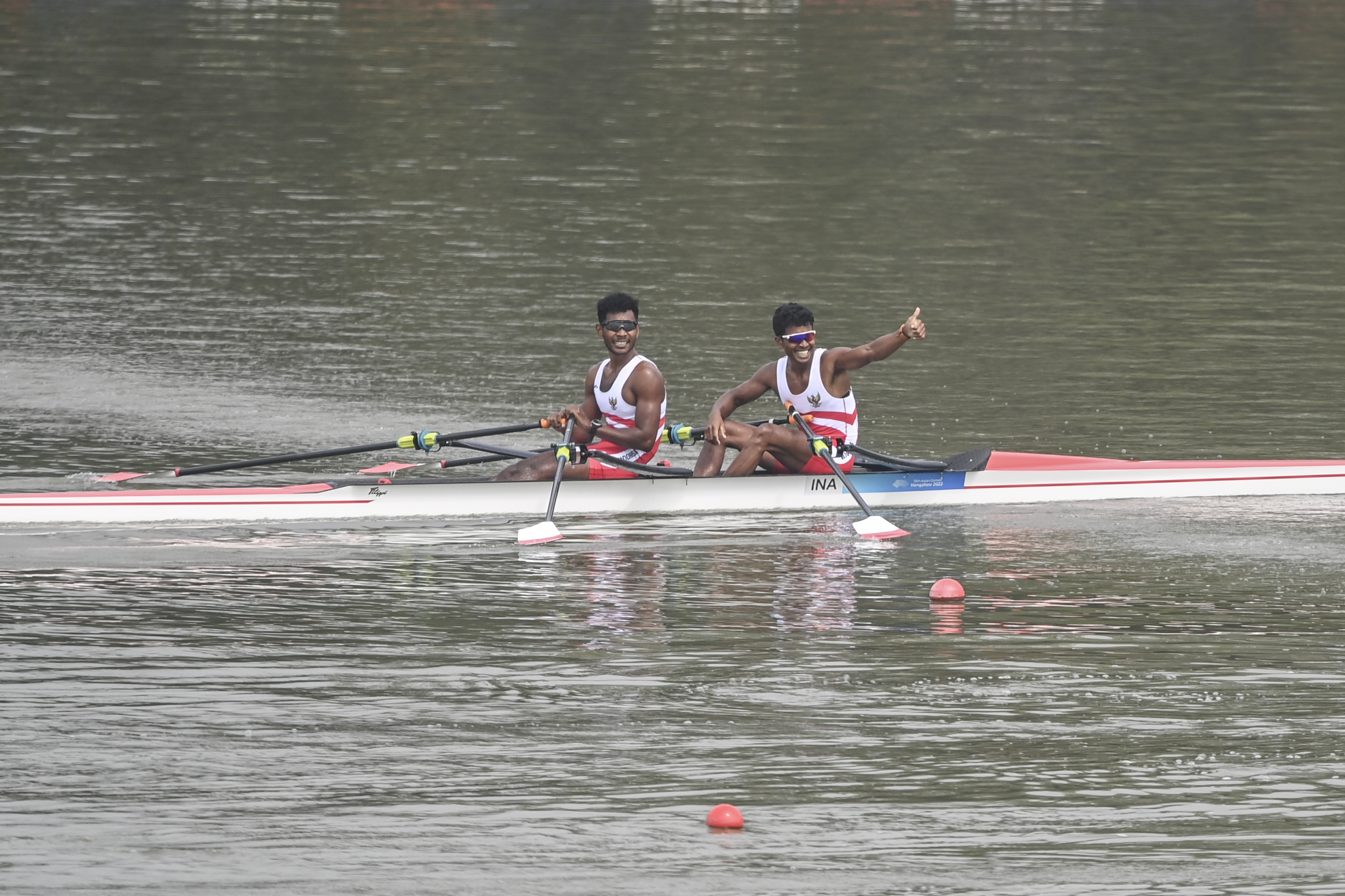 Pedayung putra Indonesia Memo dan Ihram melakukan selebrasi usai mencapai garis finis di final nomor Doubles Sculls Asian Games 2022.