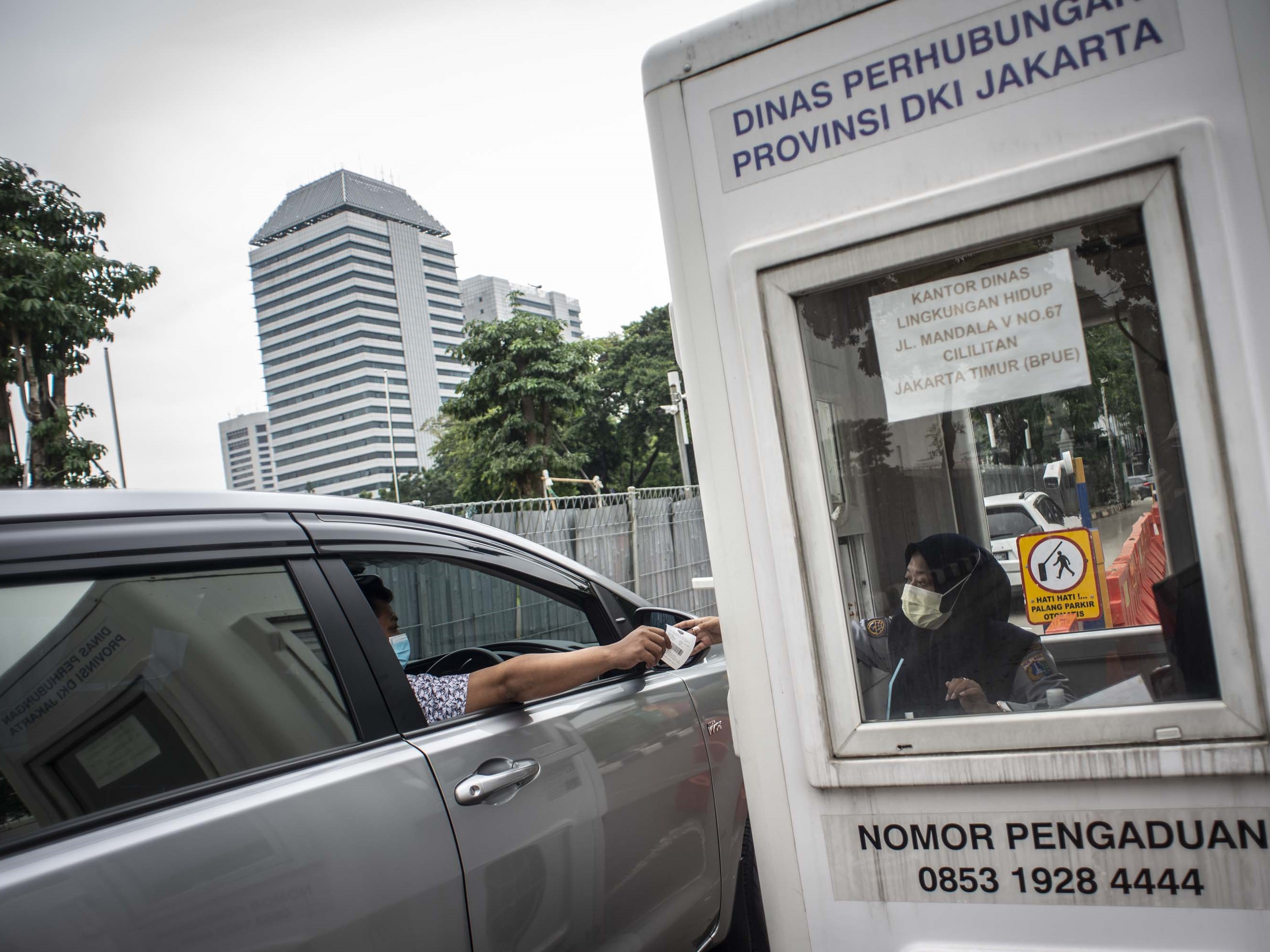 Pengendara mobil menyerahkan karcis parkir ke petugas di lapangan IRTI Monas, Jakarta Pusat, Jakarta, Rabu (23/6/2021).