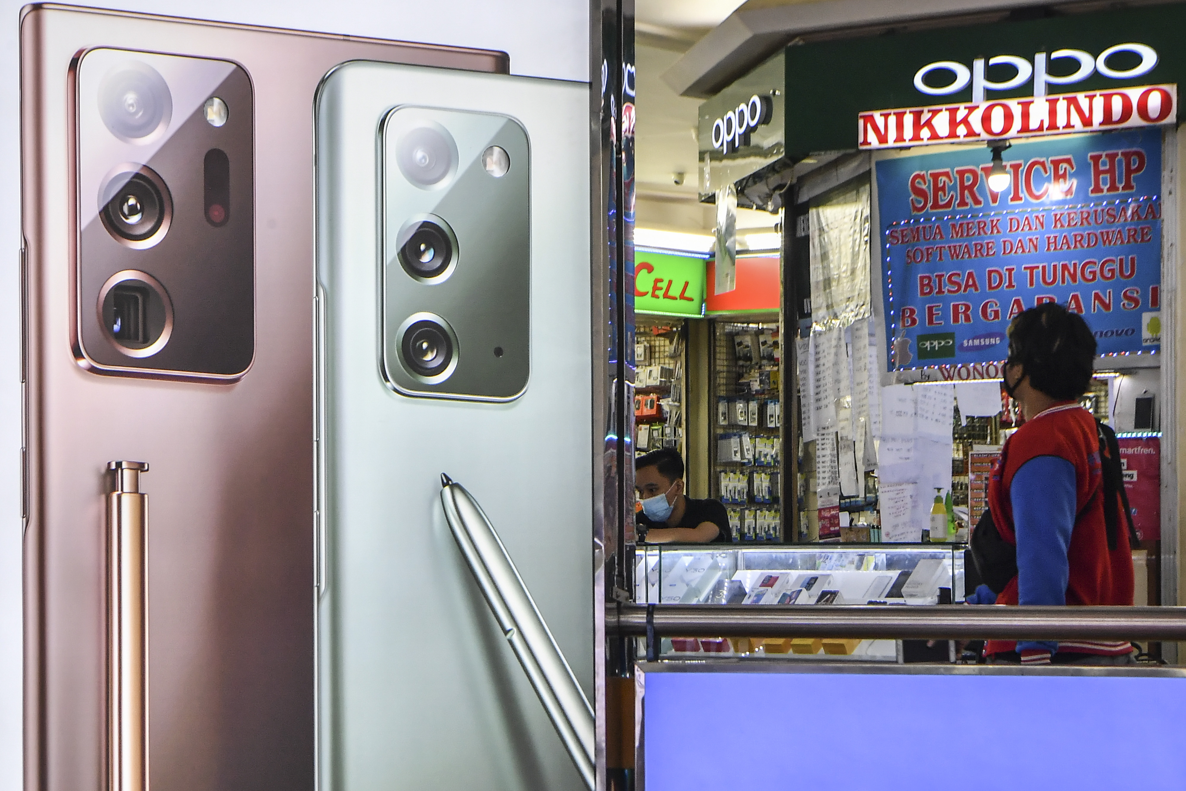 Seorang pengunjung melintas di depan toko di salah satu pusat penjualan ponsel di Jakarta.