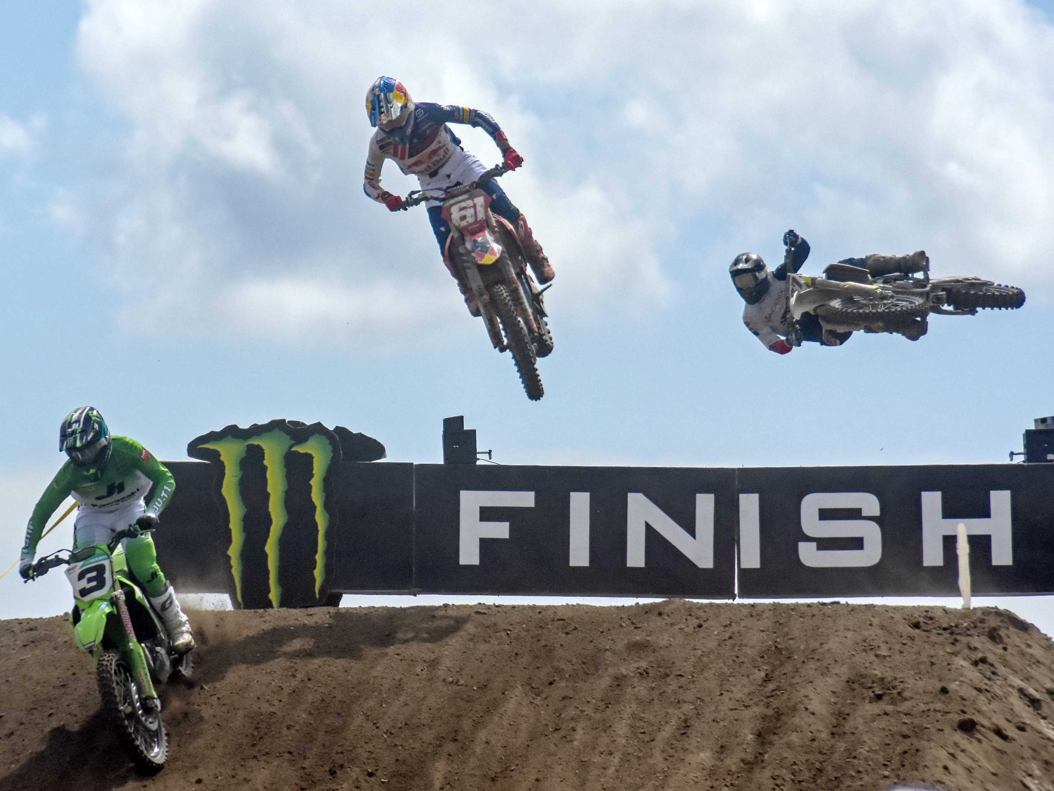 Pembalap Kawasaki Racing Team MXGP Romain Febvre (kiri) melakukan lompatan bersama pembalap tim Red Bull GasGas Jorge Prado (tengah).