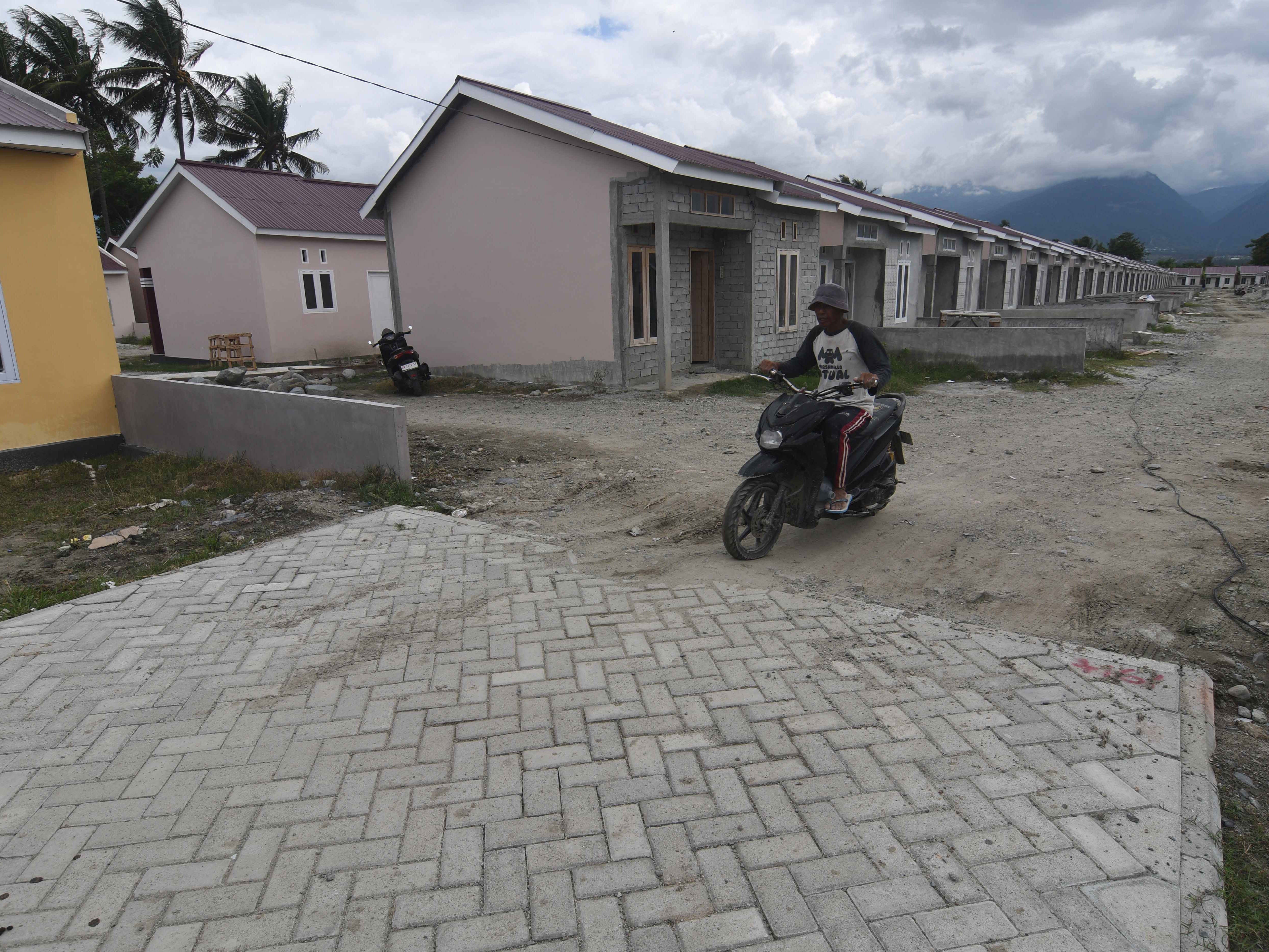 Pekerja melintas di sekitar proyek pembangunan perumahan bersubsidi di Kabupaten Sigi, Sulawesi Tengah, Rabu (14/6/2023).