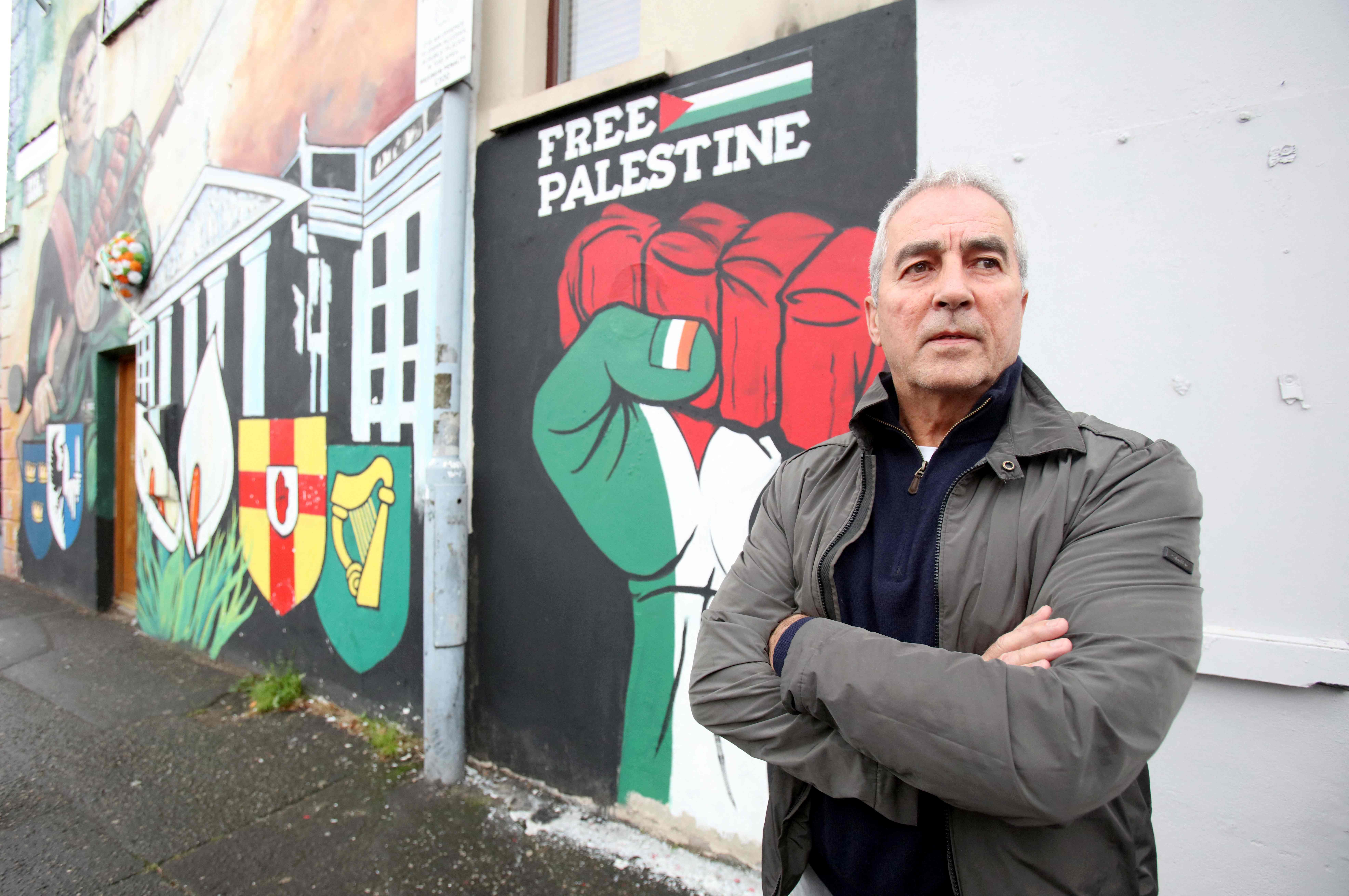 Pat Sheehan, seorang anggota parlemen dari Sinn Fein, sayap politik paramiliter IRA di dekat mural yang mendukung Palestina.