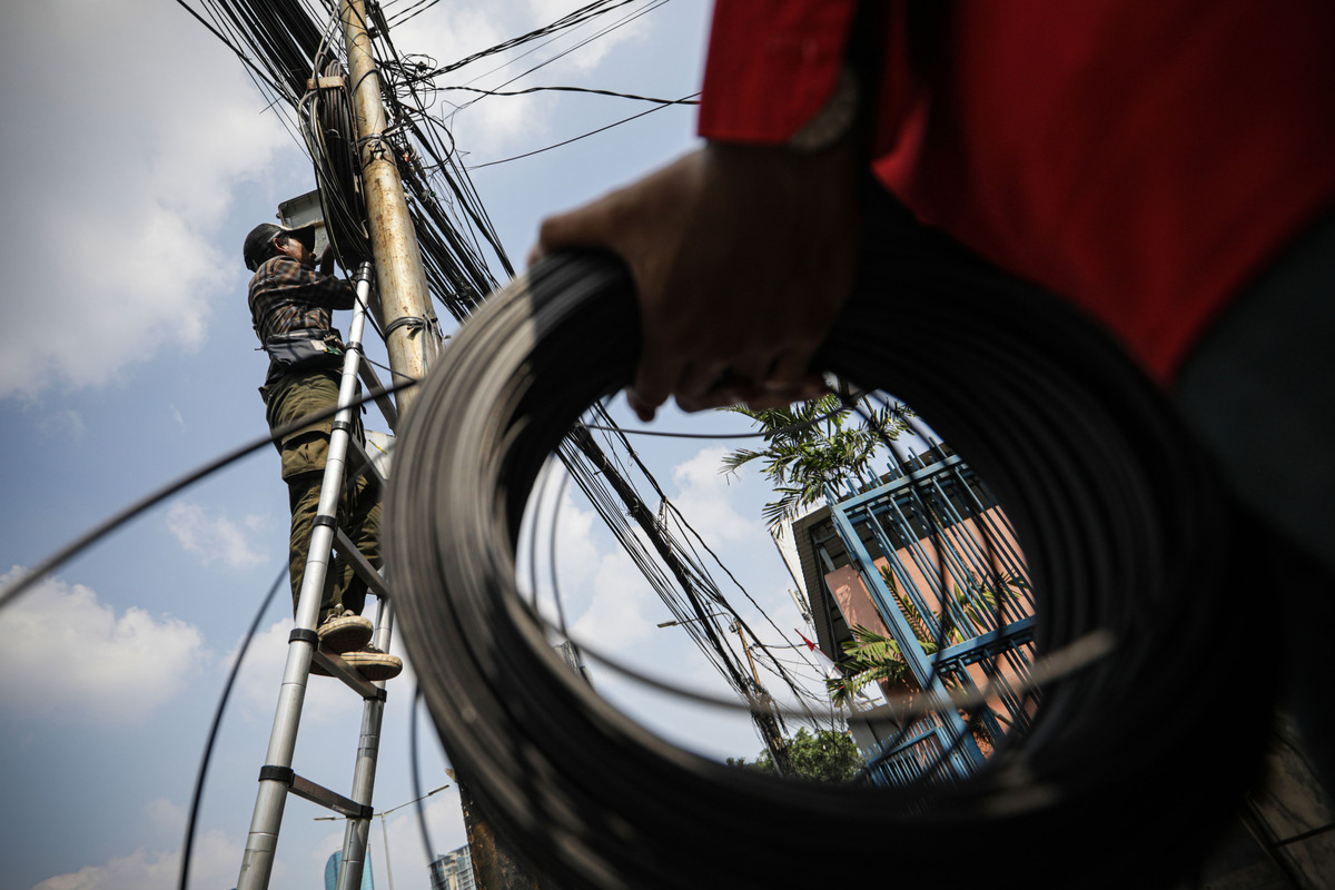 Petugas memasang kabel serat optik diantara tumpukan kabel yang semrawut di kawasan Tanah Abang, Jakarta.