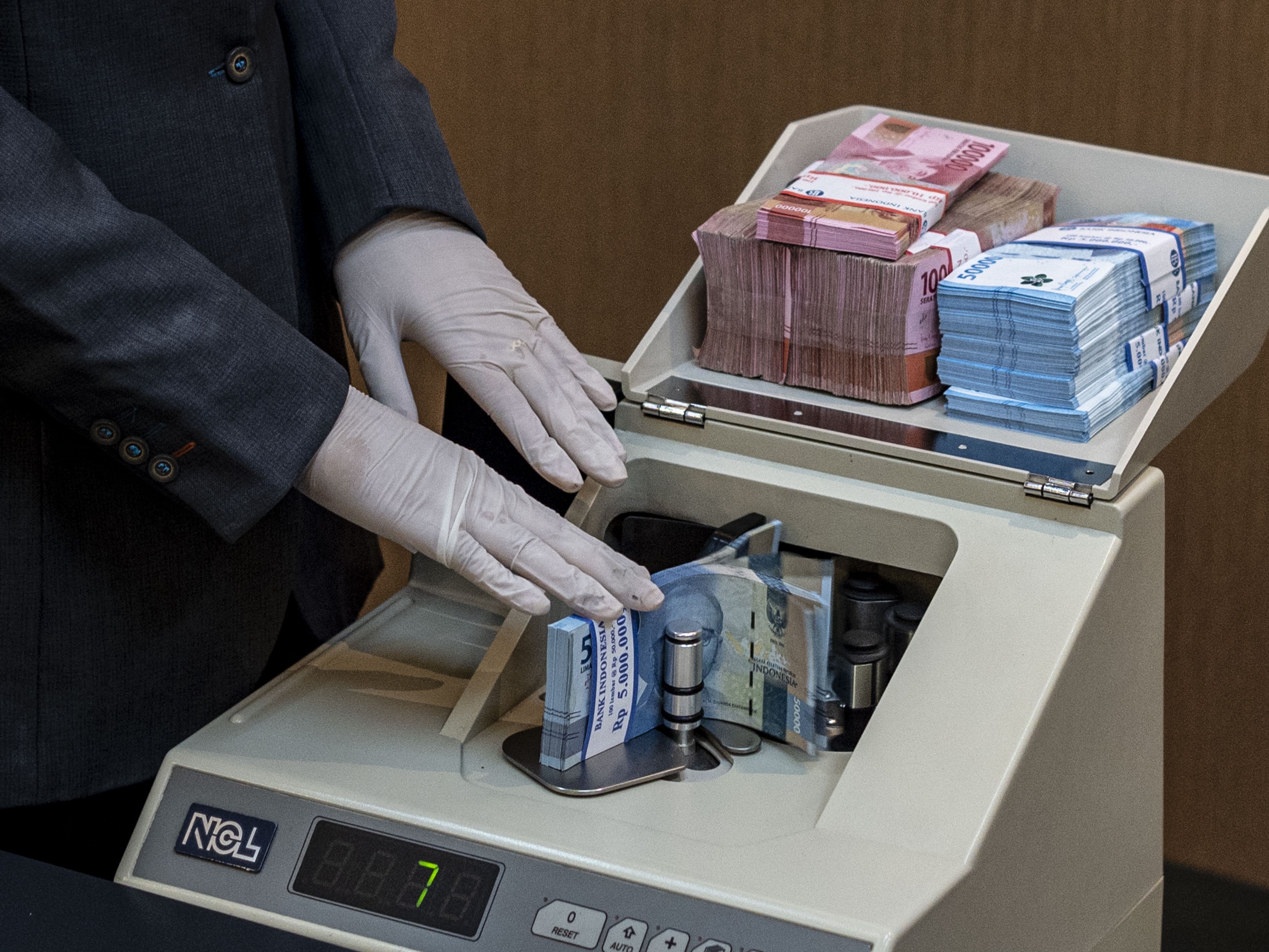 Karyawan menghitung uang di BNI KC Mega Kuningan, Jakarta.