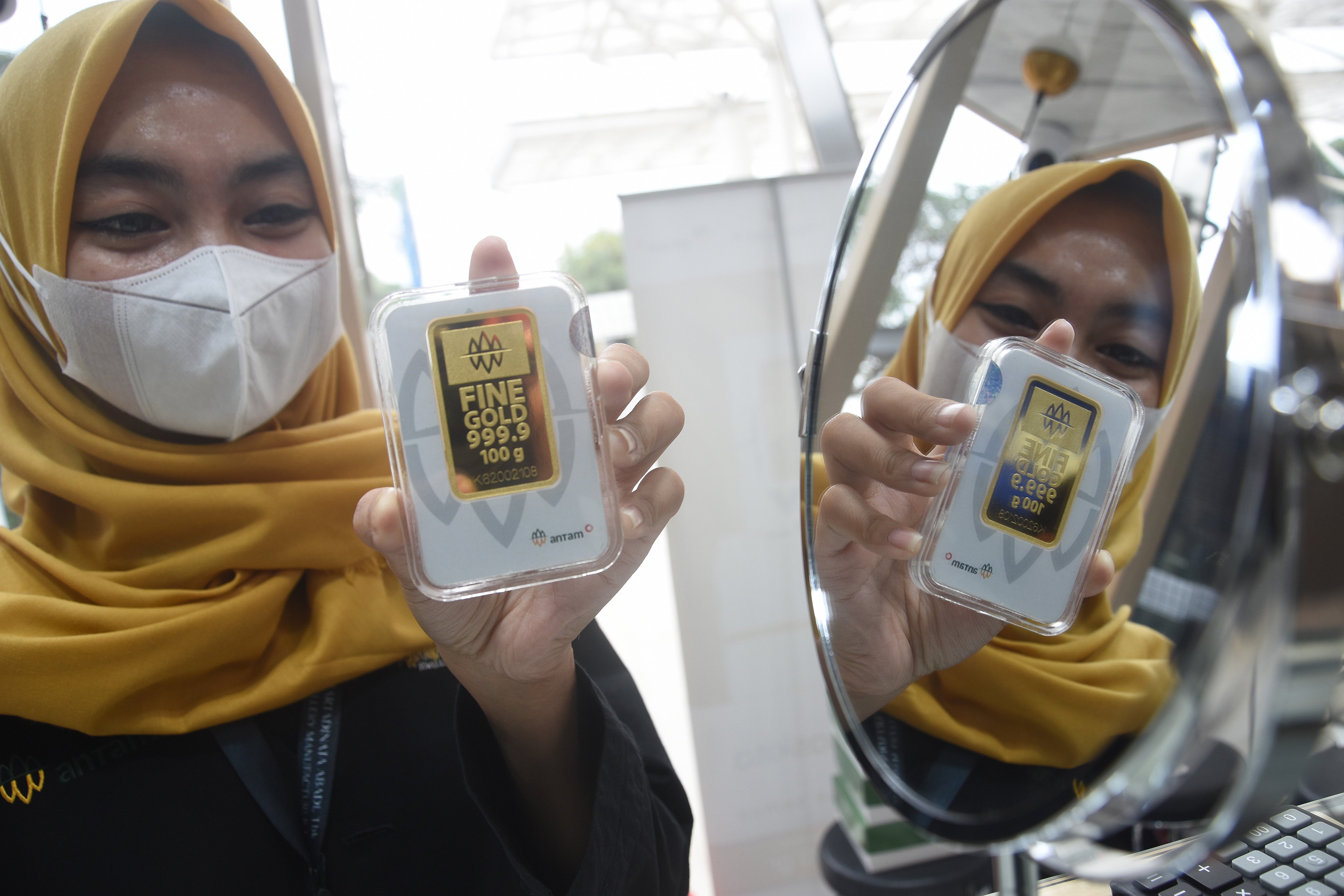  Seorang pegawai menunjukkan kepingan emas di gerai penjualan emas di Gedung Antam, Jakarta, Selasa (12/7/2022).