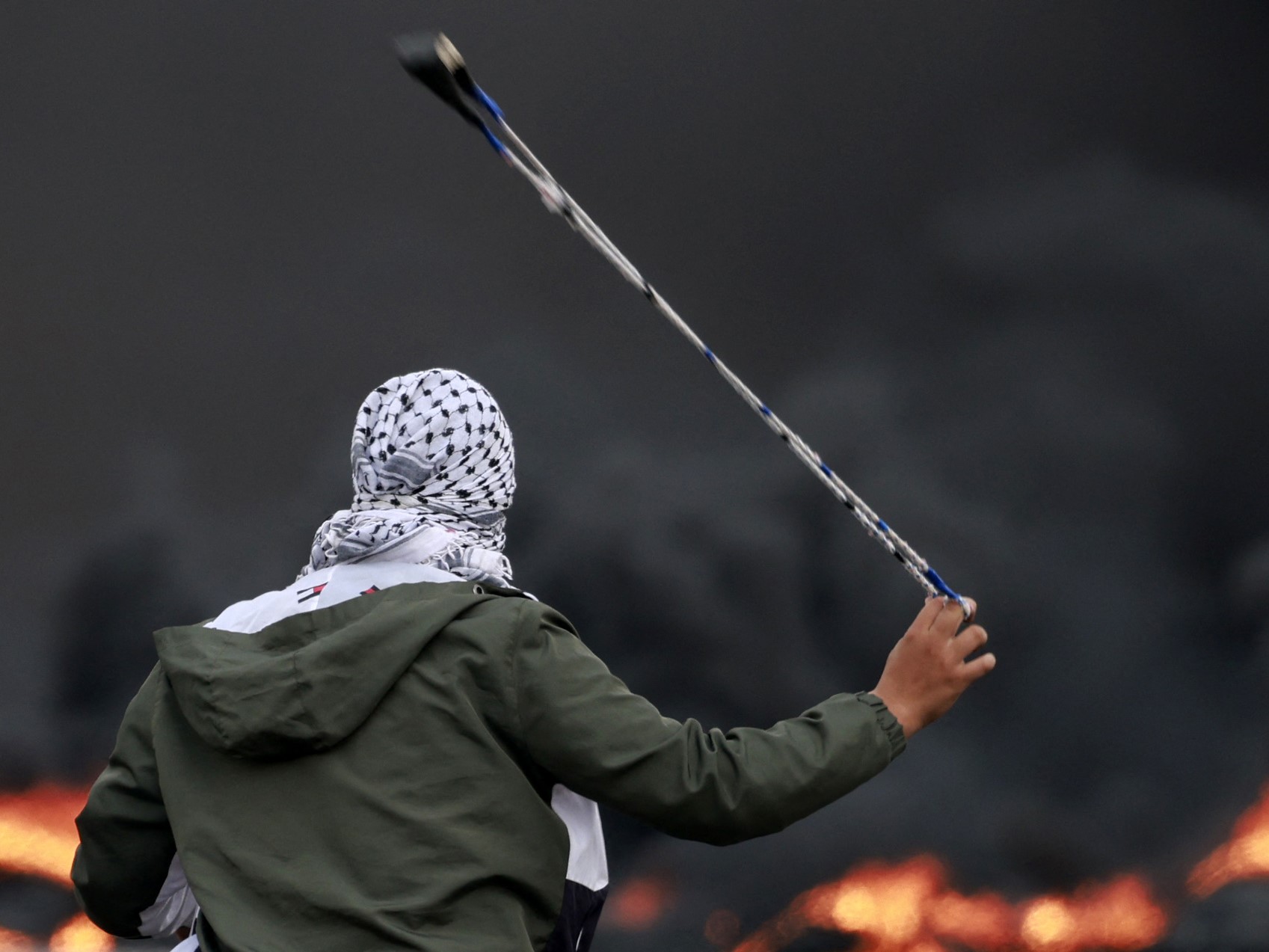 Seorang warga Palestina melemparkan batu ke arah pasukan Israel selama demonstrasi menentang pemboman Israel di Jalur Gaza, Ramallah.