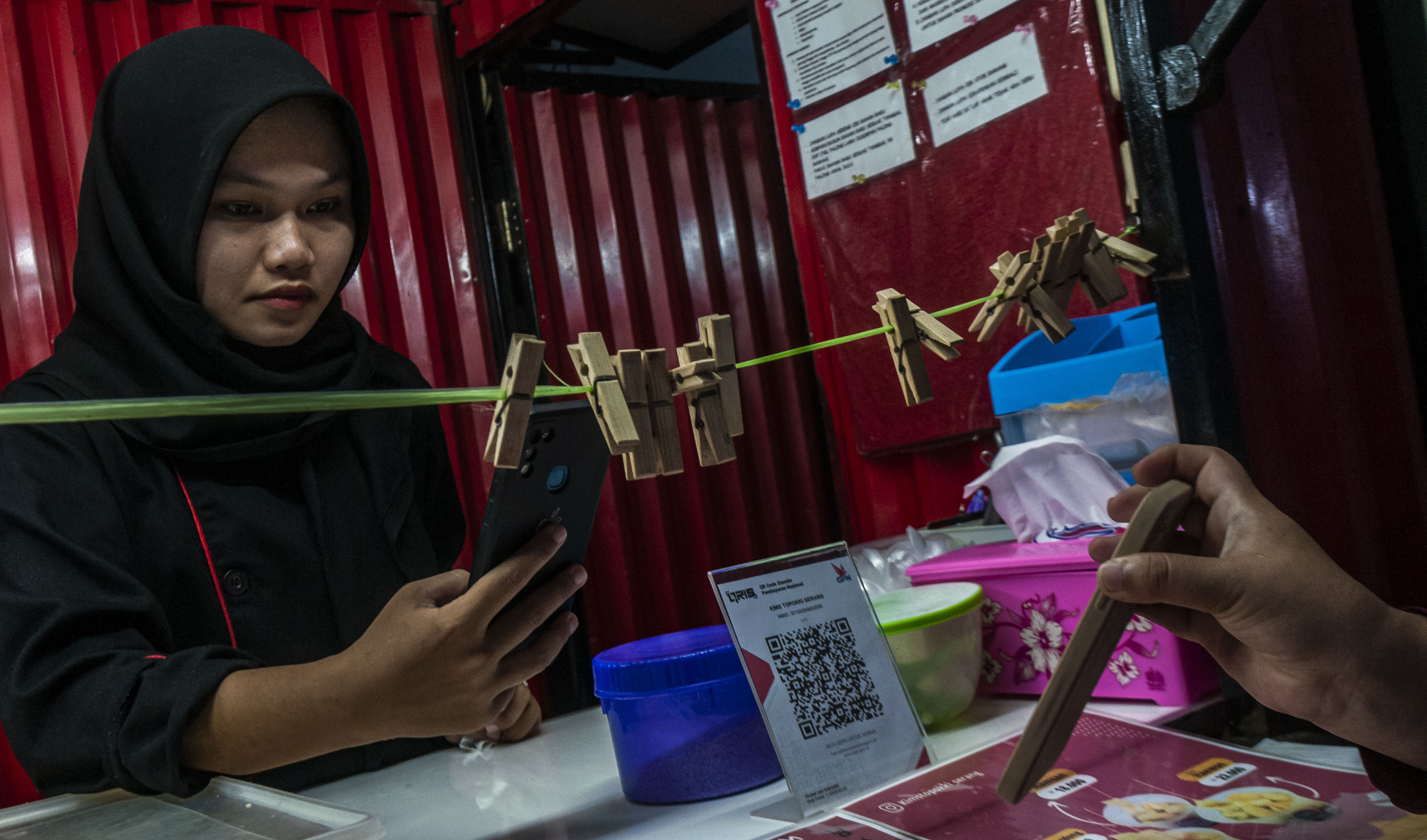 Pedagang melayani pembeli memindai kode Quick Response