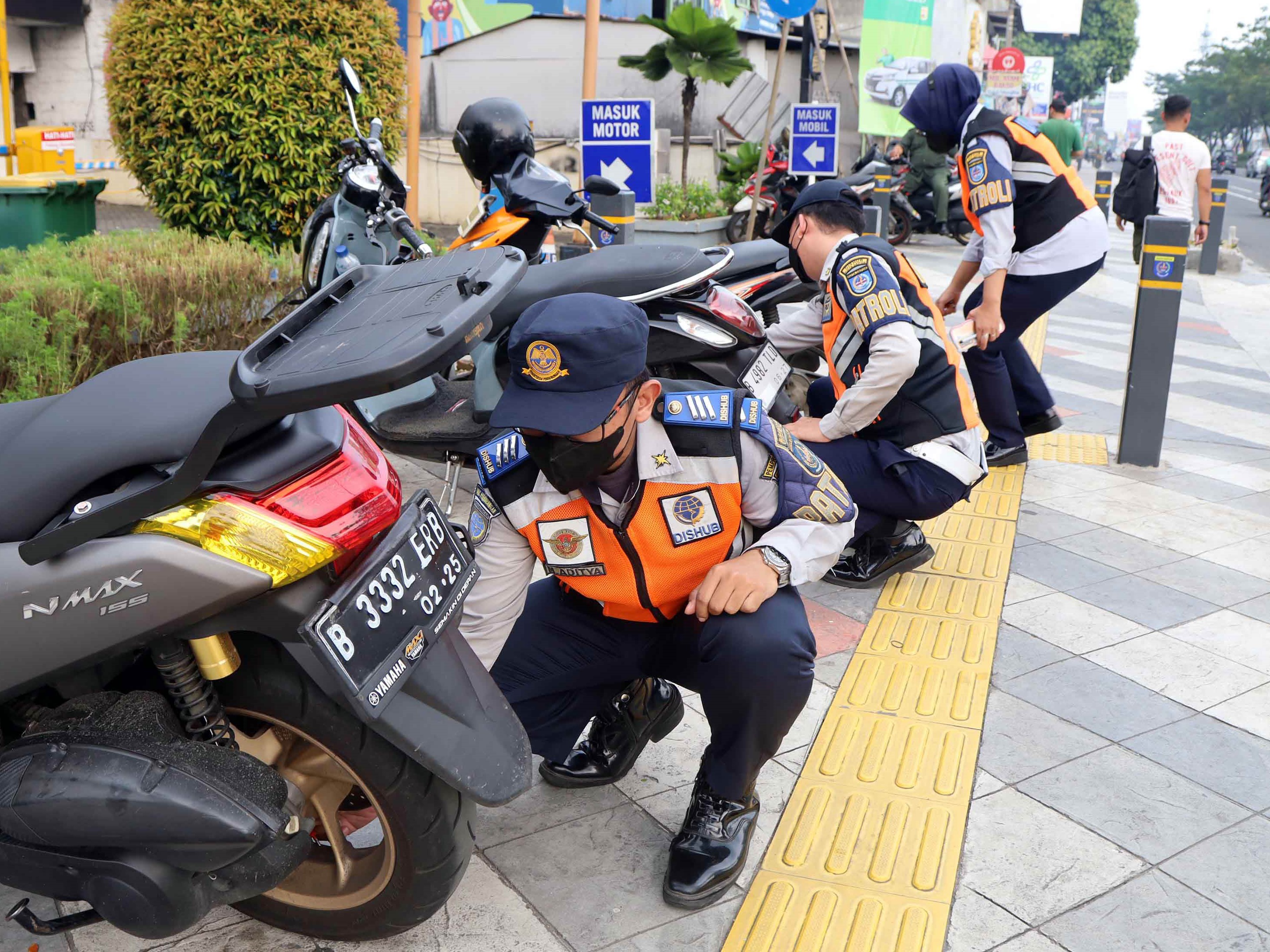 Petugas Dishub Kota Depok mengempeskan ban motor yang parkir sembarangan di trotoar Jalan Margonda Raya, Depok, Juli lalu.