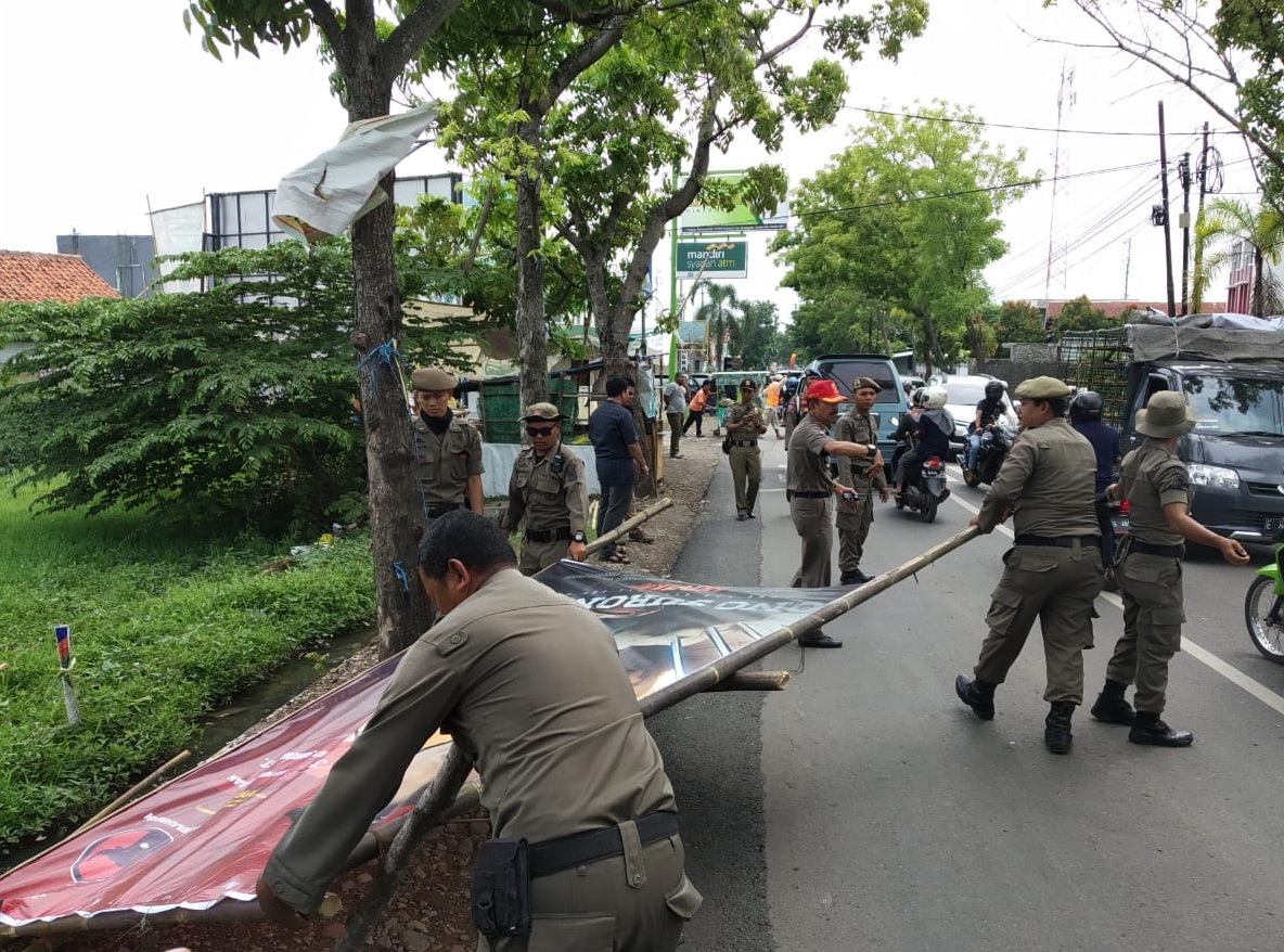 Sejumlah anggota Satpol PP Kota Cirebon menurunkan alat peraga kampanye yang melanggar aturan