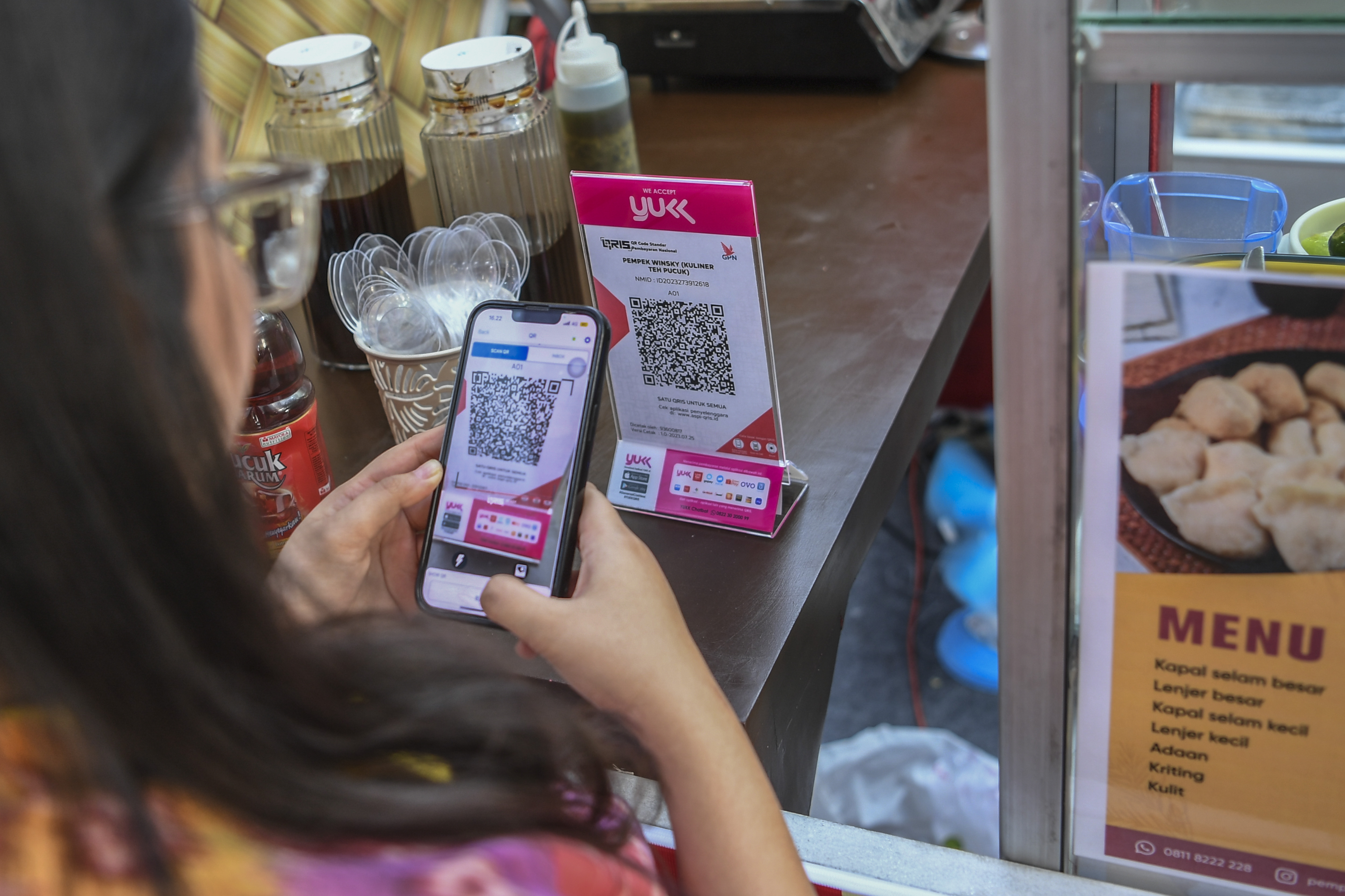  Pembeli melakukan pembayaran secara digital menggunakan QRIS di Jakarta, Jumat (28/7).