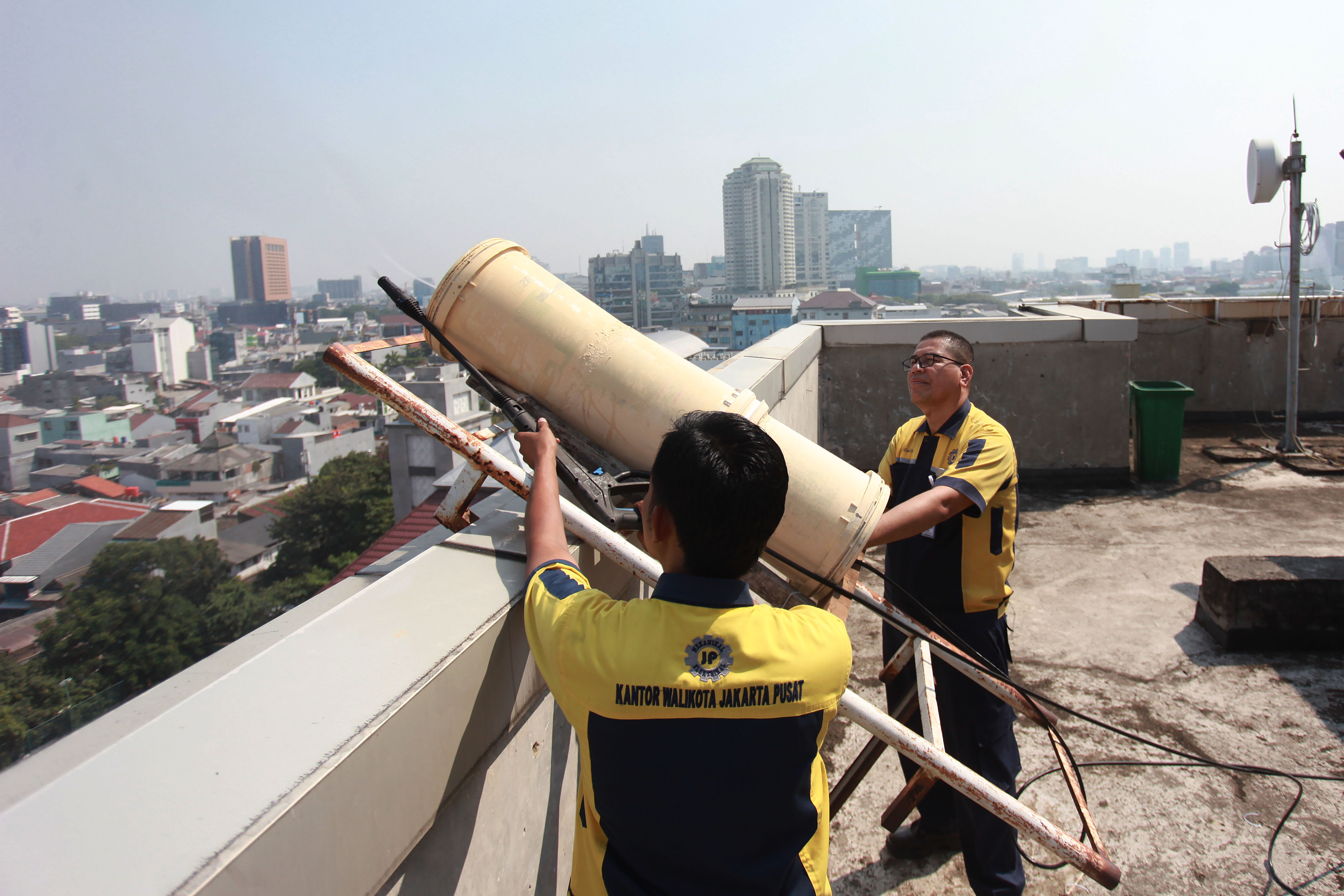 Pekerja menyemprotkan air menggunakan water mist generator di Kantor Walikota, Jakarta Pusat, Jakarta.