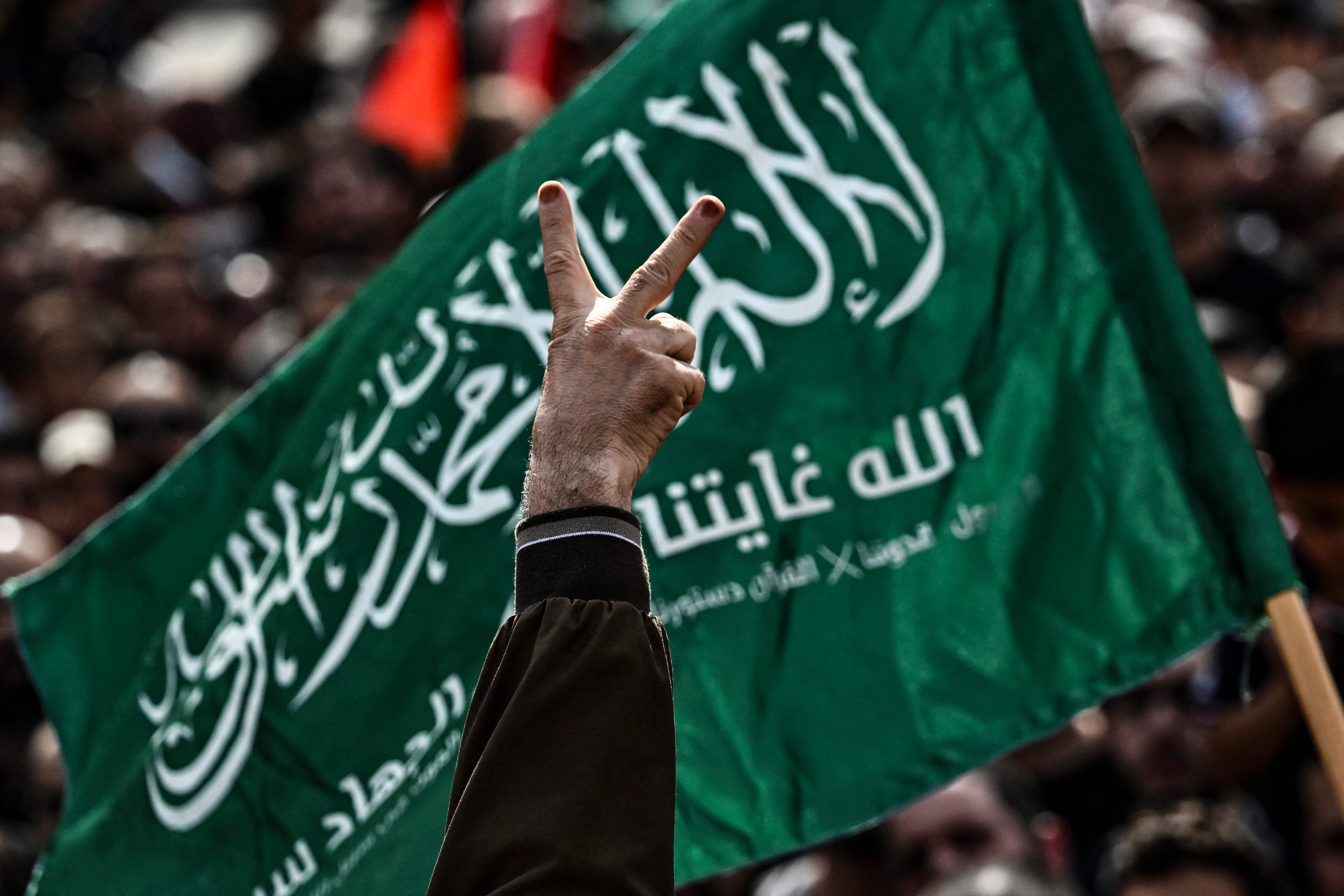 Tanda kemenangan di depan bendera Hamas. saat aksi solidaritas Palestina di Ramallah, Jumat (27/10).