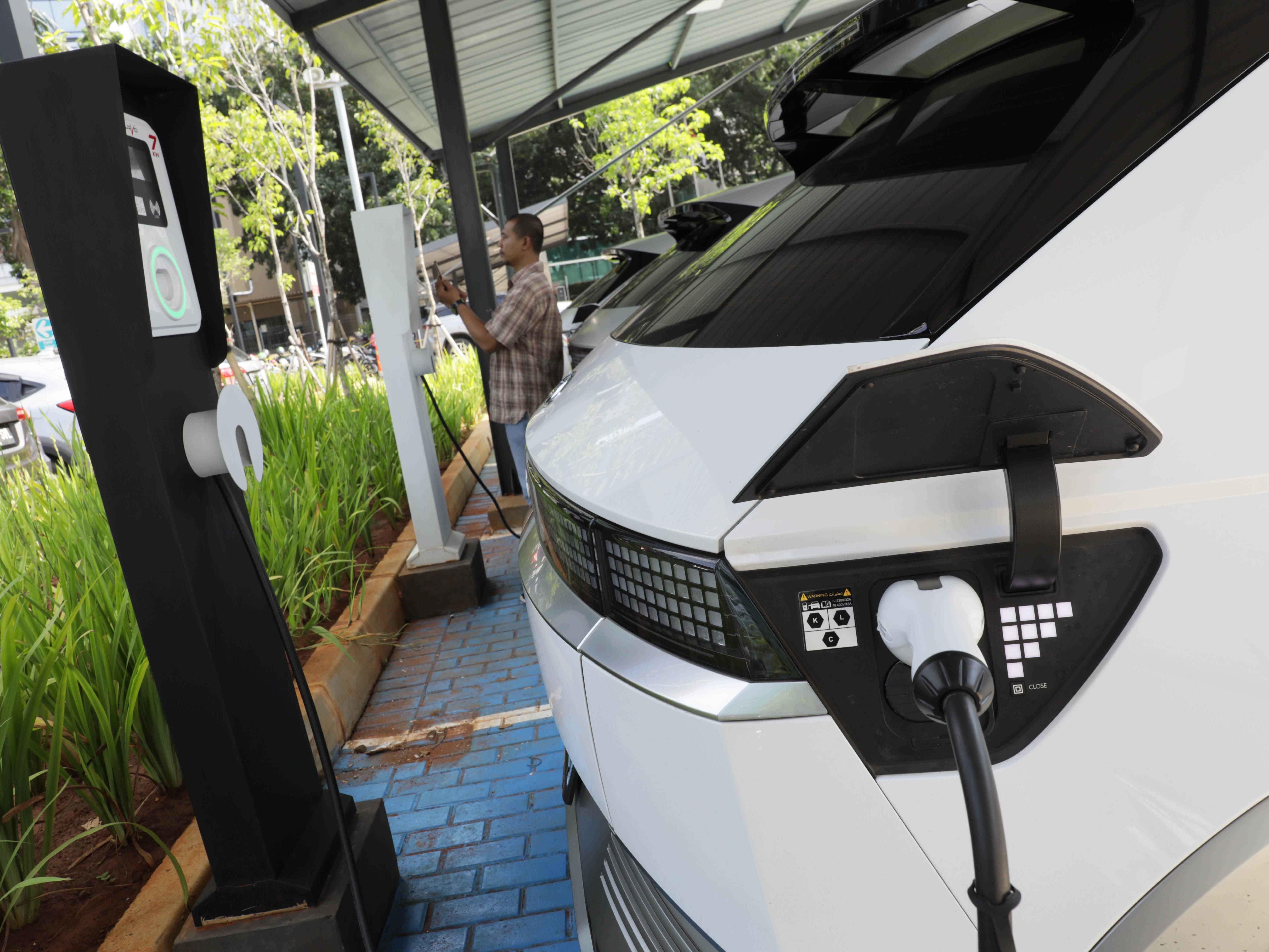 Pengemudi melakukan scan QR saat melakukan pengisian daya listrik baterai mobil listrik di Stasiun Pengisian Kendaraan Listrik Umum.