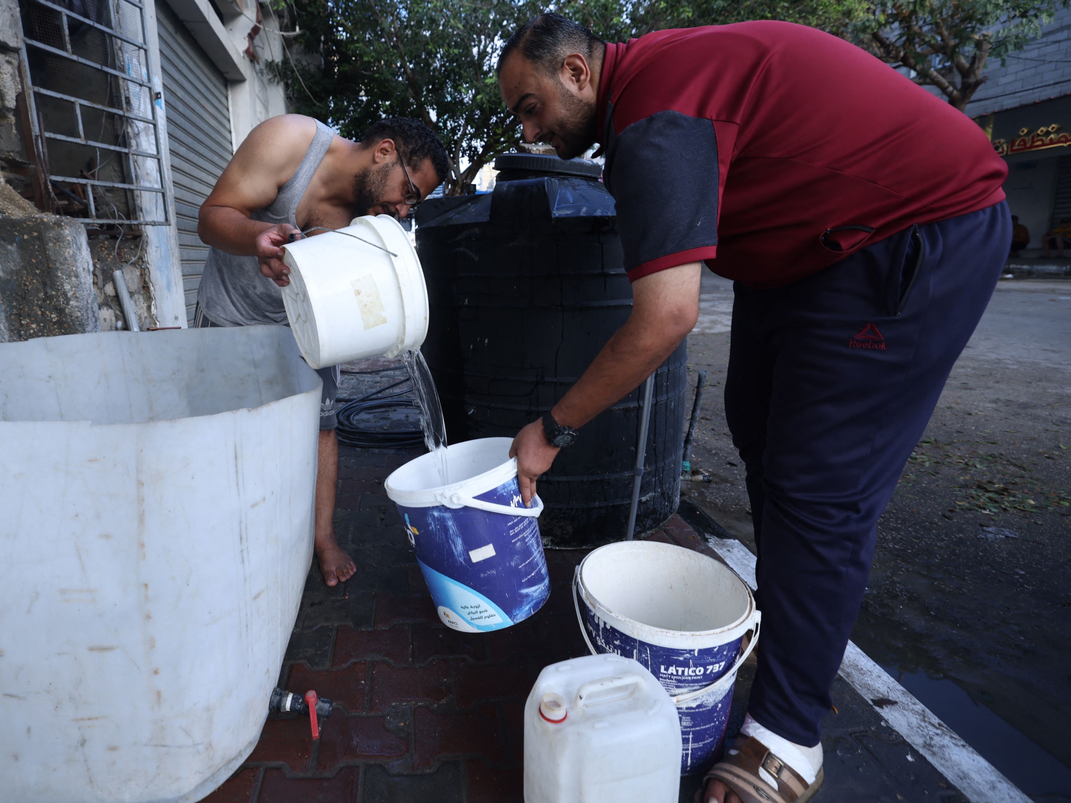 Seorang pria Palestina mengisi ember dengan air di kamp pengungsi Rafah, Jalur Gaza selatan, pada 17 Oktober 2023.