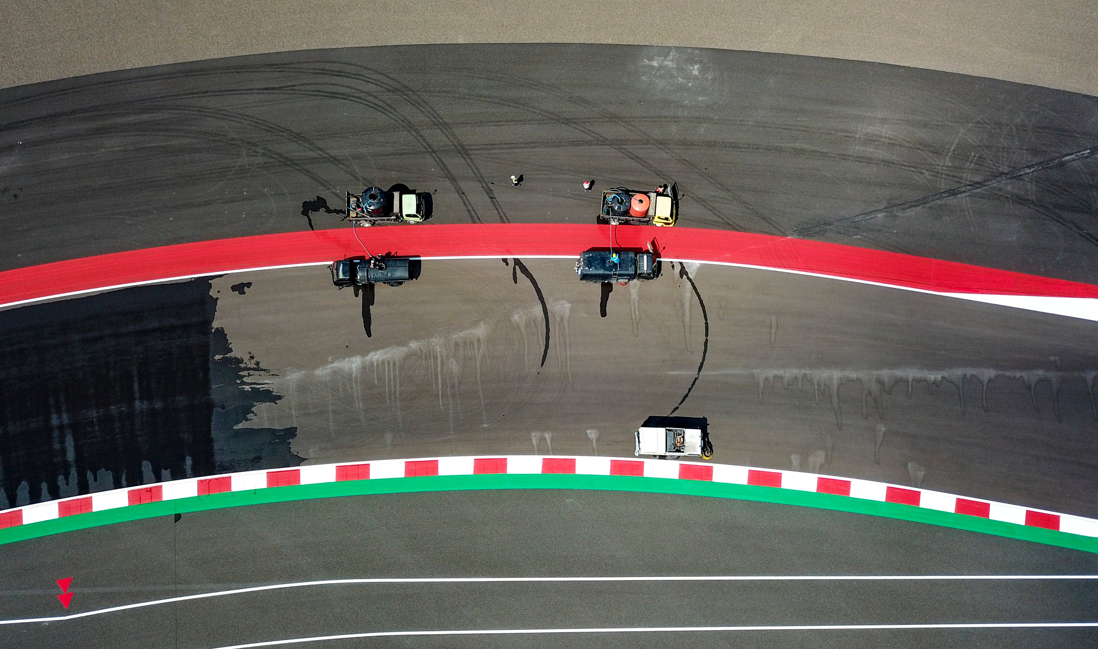 Foto udara memperlihatkan sejumlah petugas membersihkan lintasan sirkuit Pertamina Mandalika International Street Circuit, Selasa (3/10). 